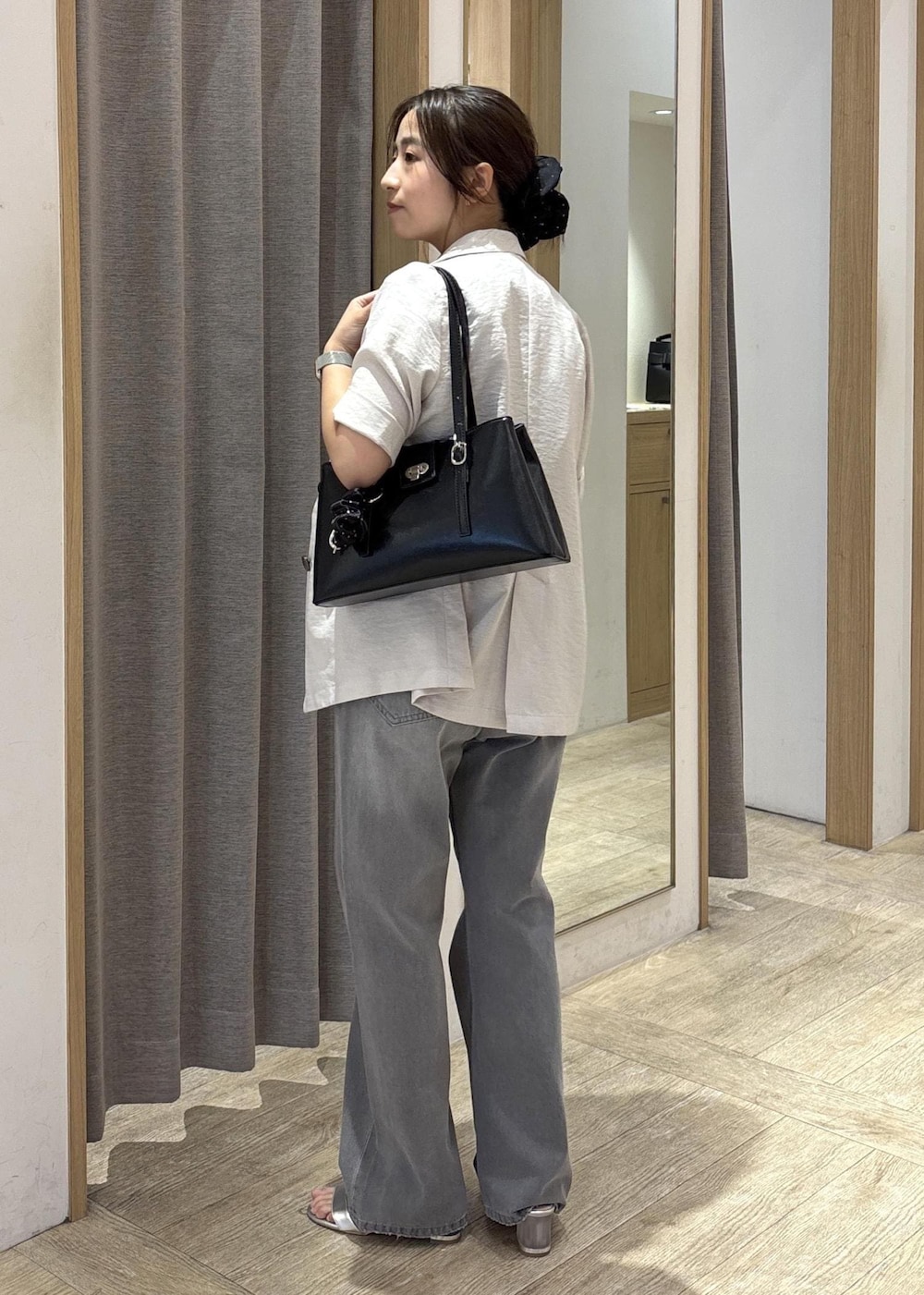 ブラック系のトートバッグ、ホワイト系のテーラードジャケット、グレー系のデニムパンツを着用したレディースの夏コーディネートの4枚目の写真