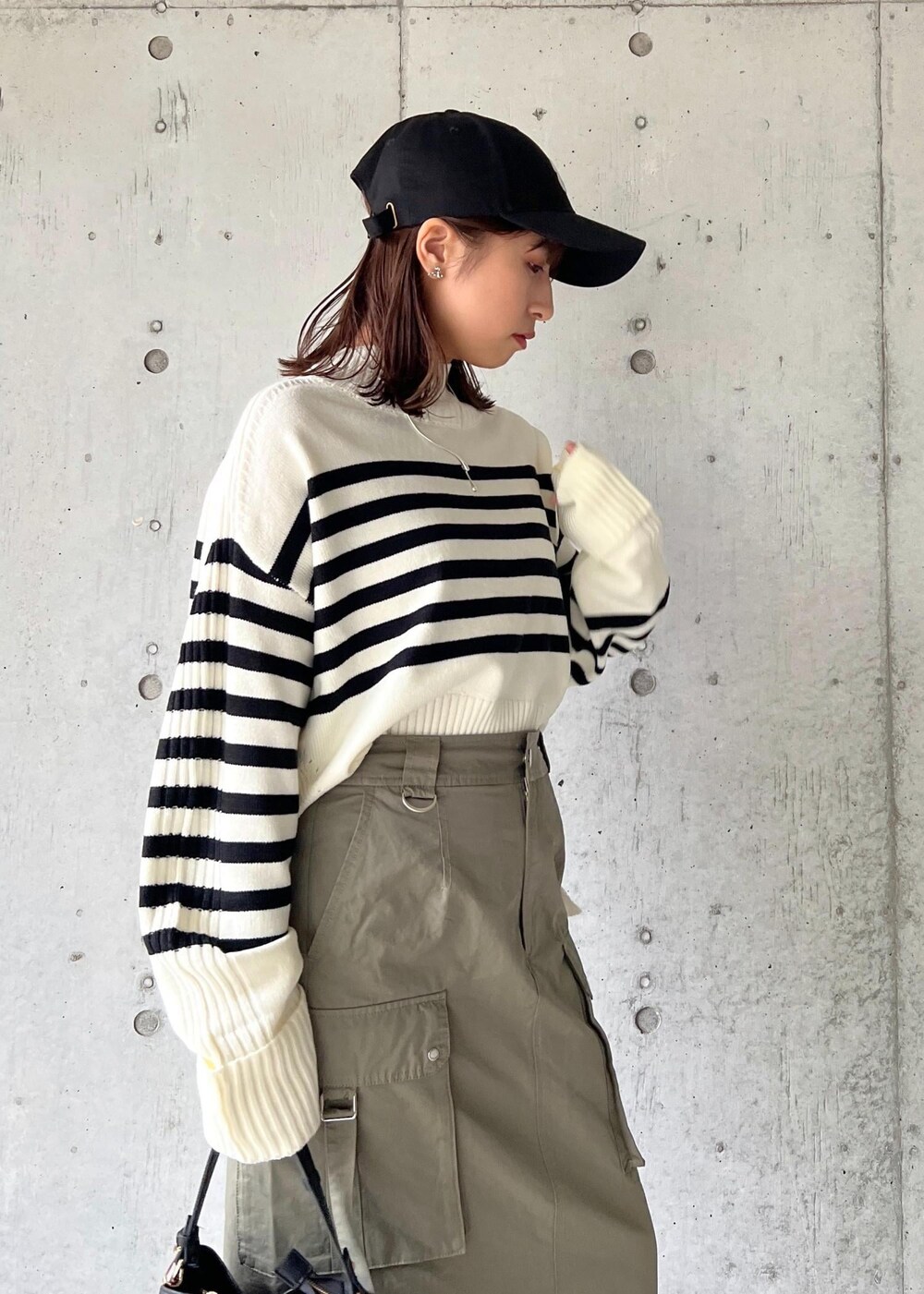 ブラック系のブーツ、グリーン系のスカート、ホワイト系のニット/セーターを着用したレディースの秋コーディネートの8枚目の写真