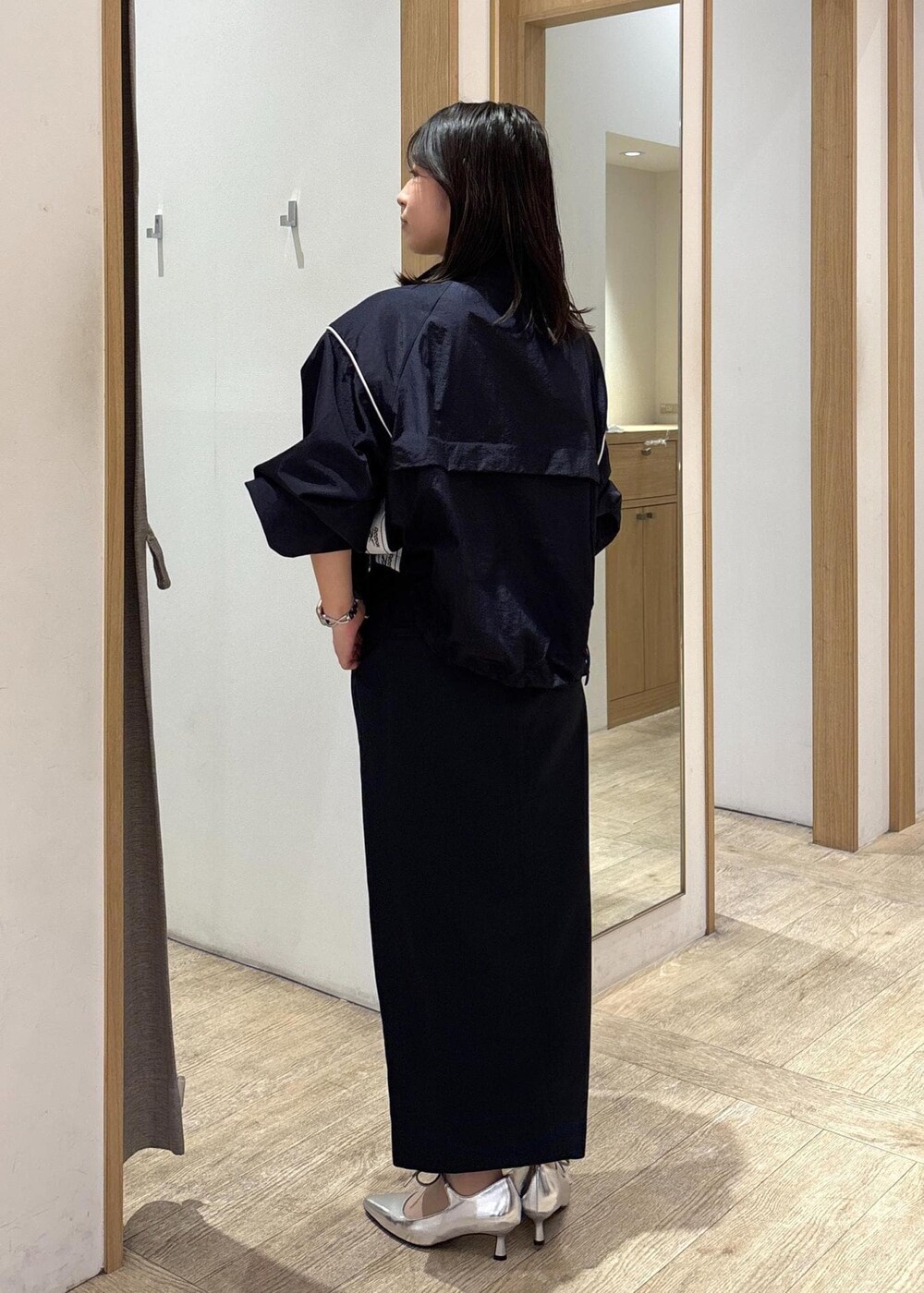 グレー系のショルダーバッグ、ブルー系のスカート、シルバー系のパンプスを着用したレディースの春コーディネートの3枚目の写真