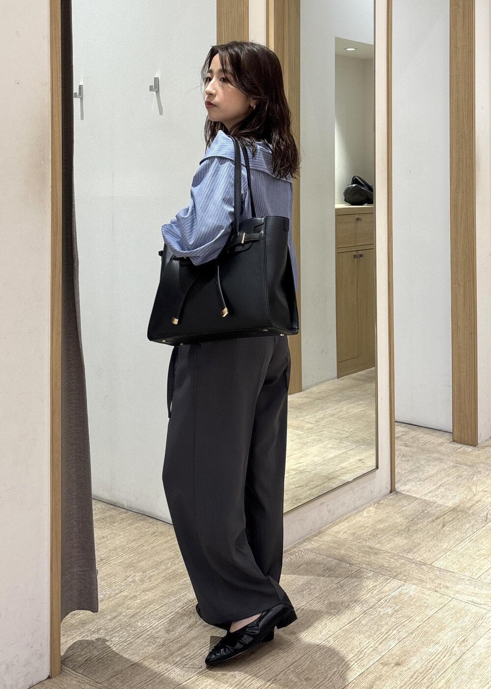 ブラック系のトートバッグ、ブラック系のパンプス、ブルー系のシャツ/ブラウスを着用したレディースの秋コーディネートの2枚目の写真