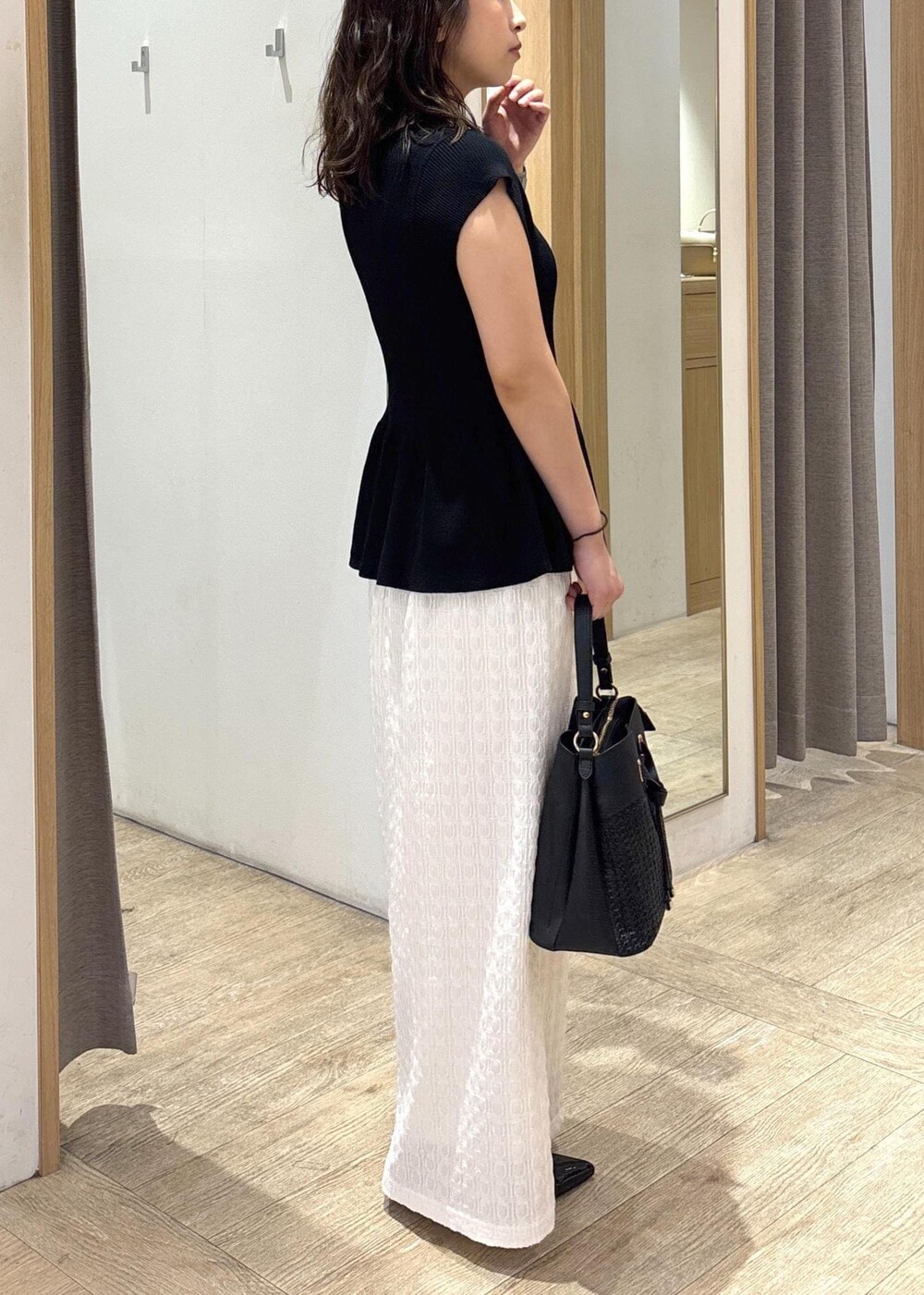 ブラック系のパンプス、ホワイト系のスカート、ブラック系のショルダーバッグを着用したレディースの夏コーディネートの4枚目の写真