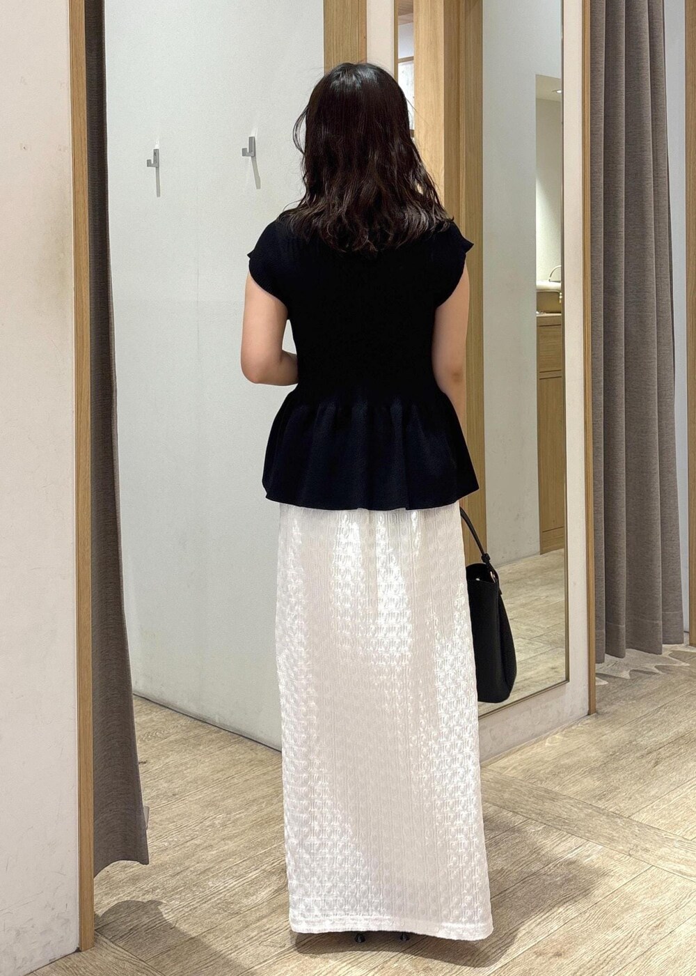 ブラック系のパンプス、ホワイト系のスカート、ブラック系のショルダーバッグを着用したレディースの夏コーディネートの3枚目の写真