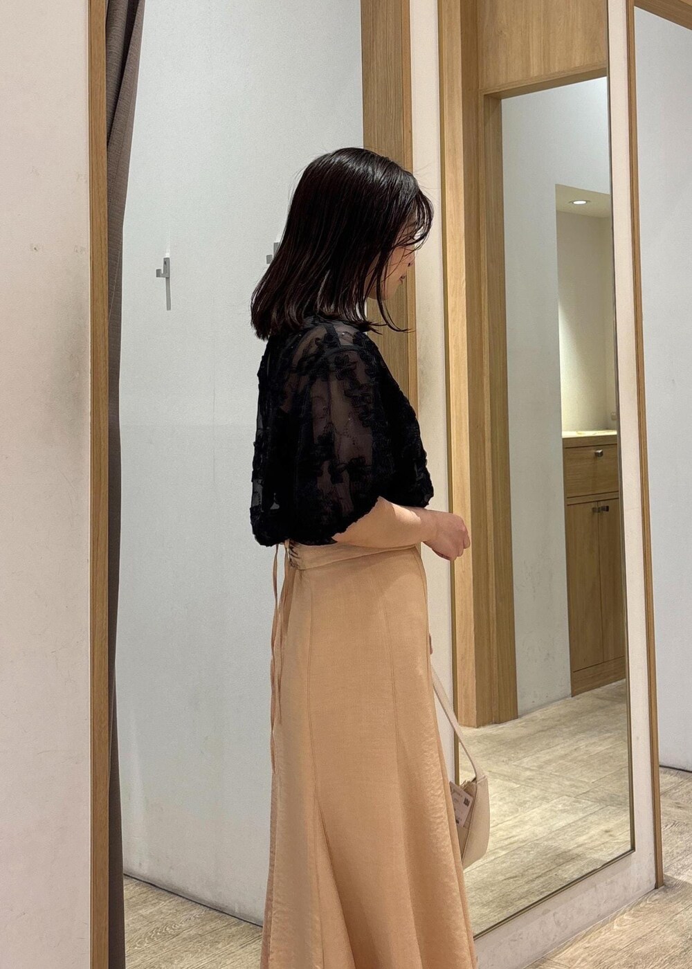 ホワイト系のハンドバッグ、シルバー系のパンプス、オレンジ系のスカートを着用したレディースの春コーディネートの9枚目の写真