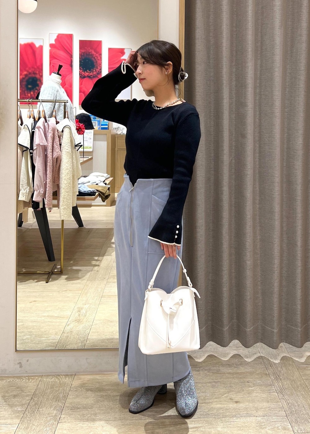シルバー系のブーツ、ブルー系のスカート、ブラック系のニット/セーターを着用したレディースの冬コーディネートの2枚目の写真
