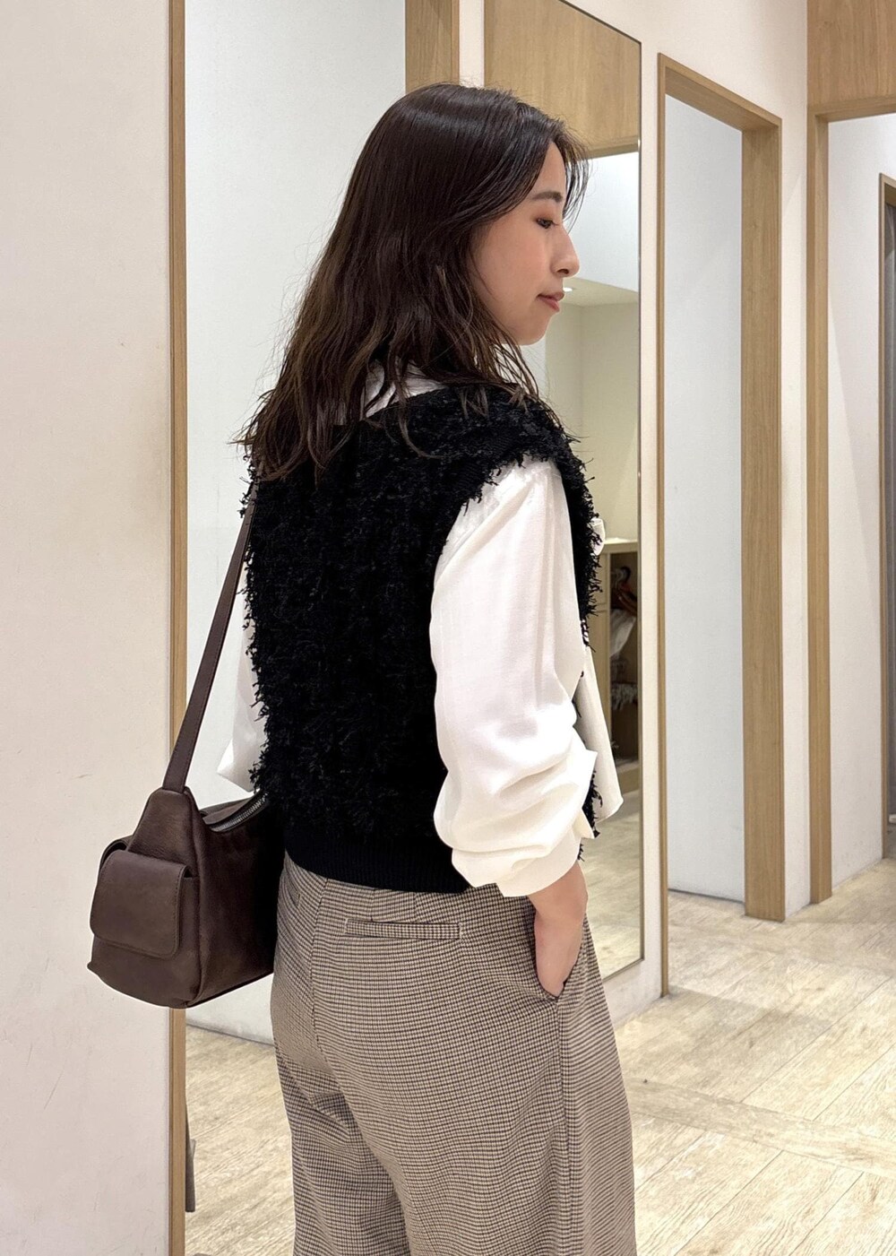 ベージュ系のスラックス、ブラウン系のショルダーバッグ、ブラック系のベストを着用したレディースの秋コーディネートの9枚目の写真