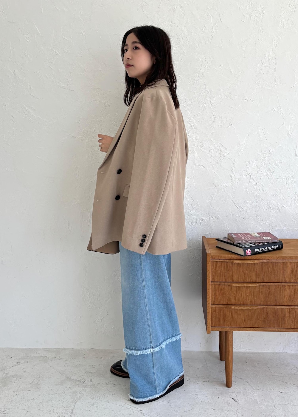 ブラック系のローファー、ホワイト系のベスト、ブルー系のデニムパンツを着用したレディースの夏コーディネートの3枚目の写真