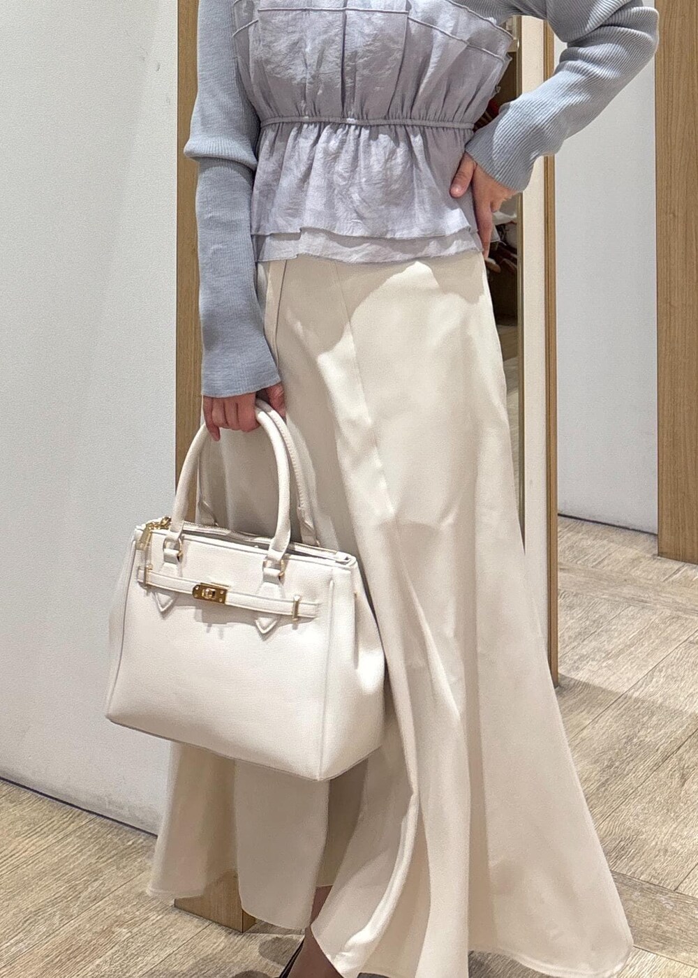 ブラック系のパンプス、ベージュ系のスカート、ブルー系のニット/セーターを着用したレディースの春コーディネートの9枚目の写真