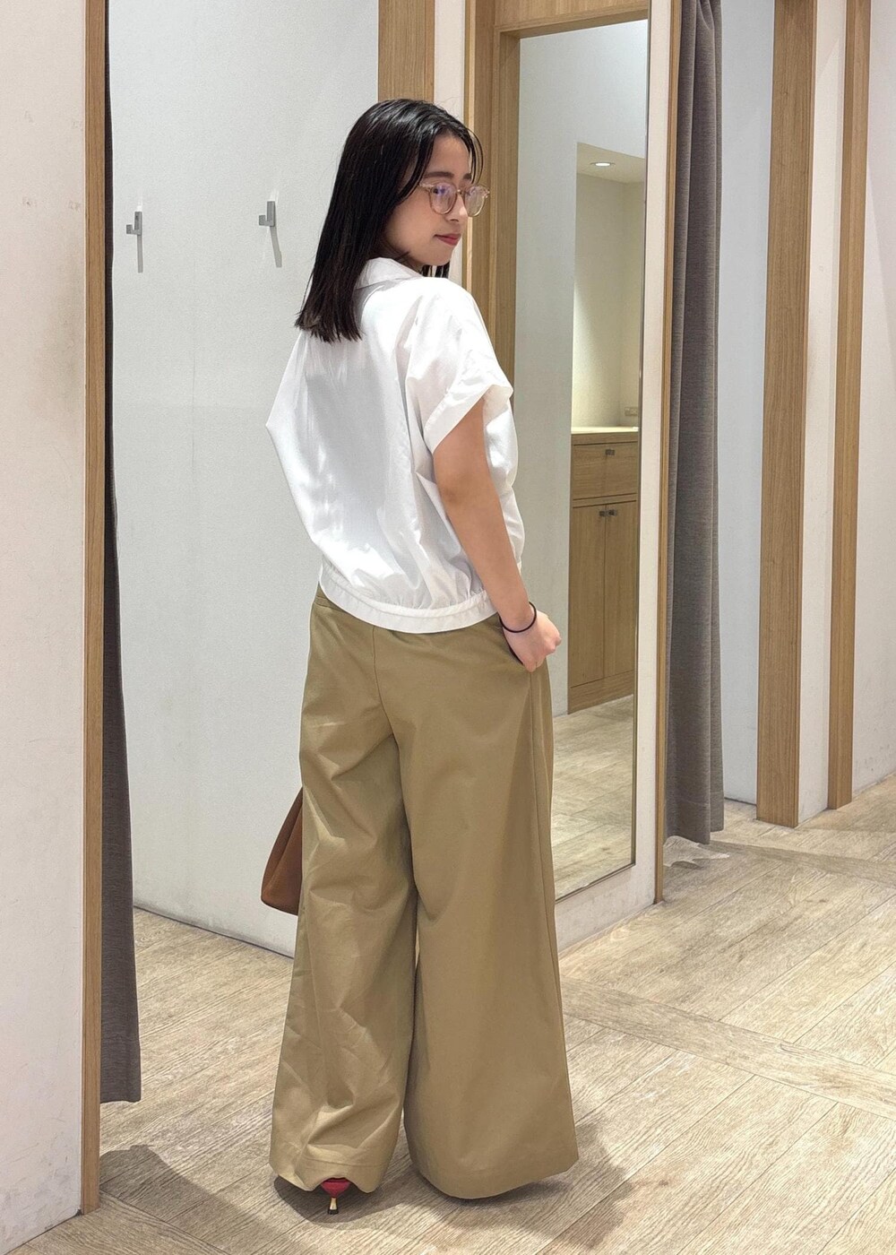 ブラウン系のショルダーバッグ、レッド系のサンダル、ホワイト系のシャツ/ブラウスを着用したレディースの夏コーディネートの2枚目の写真