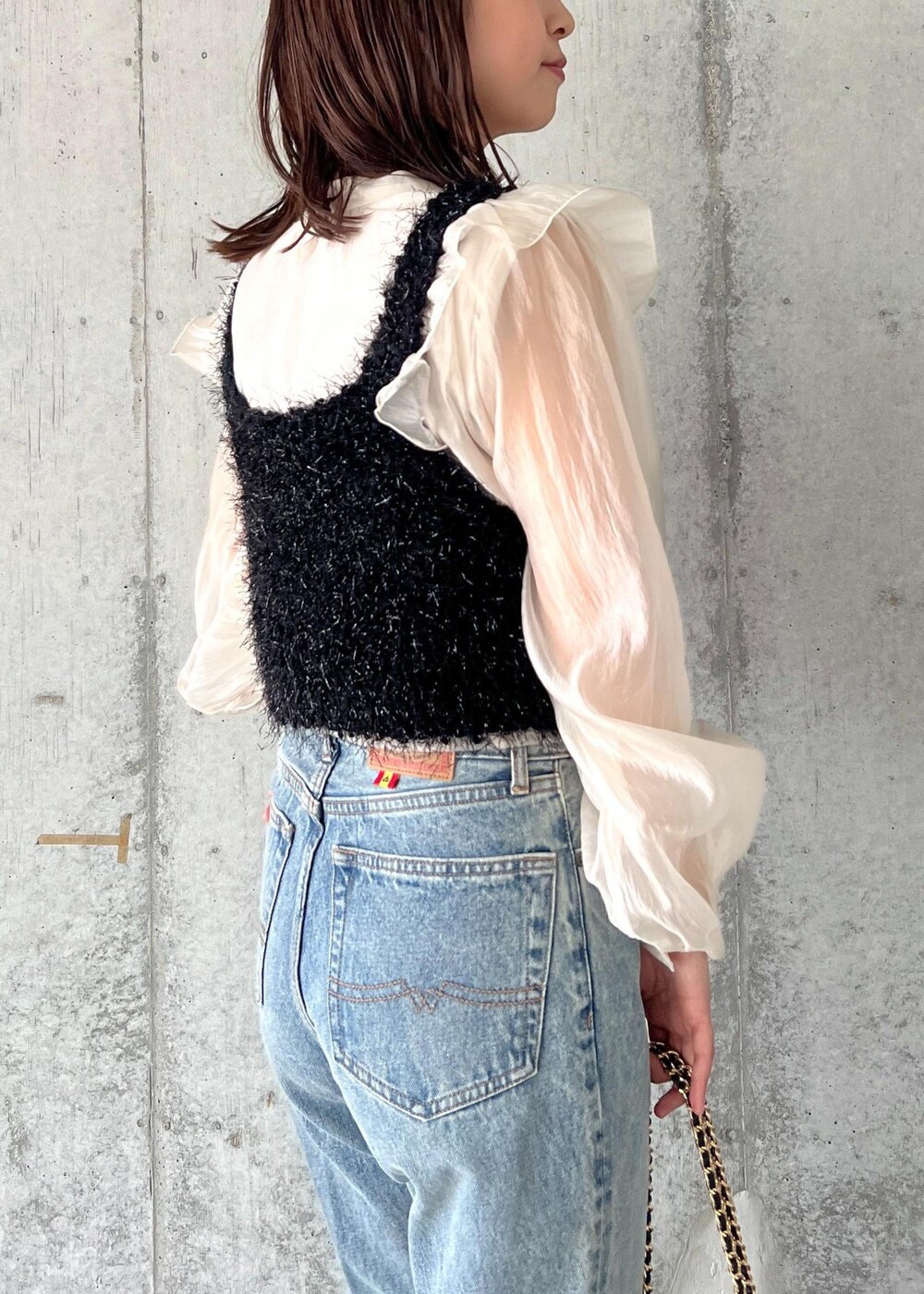 ブルー系のデニムパンツ、ブラック系のキャミソール、シルバー系のブーツを着用したレディースの秋コーディネートの8枚目の写真