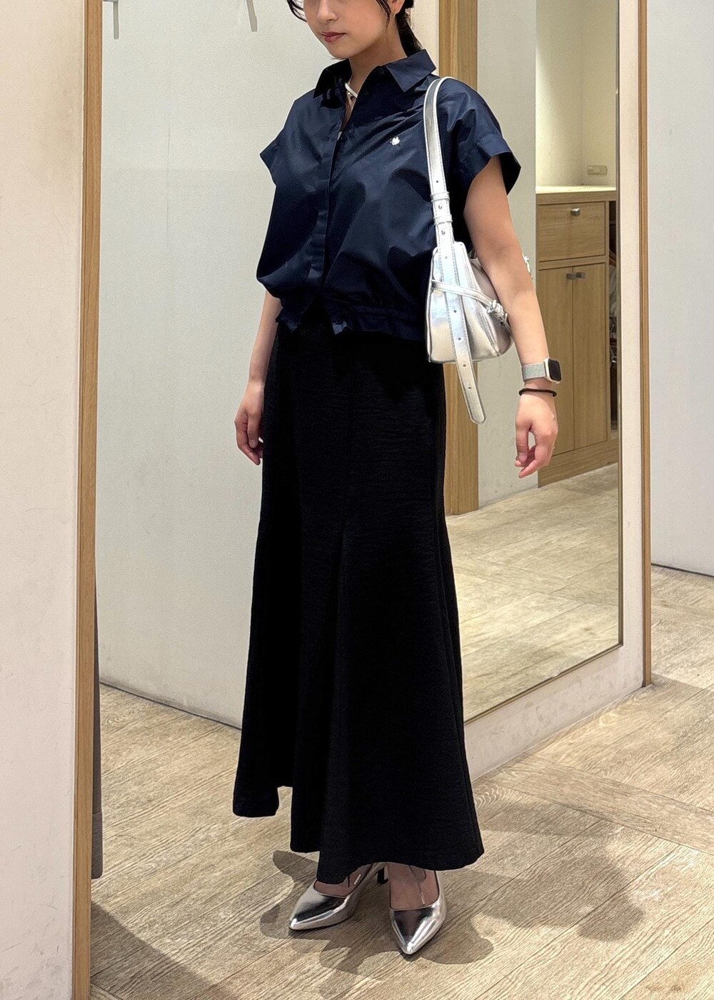 ホワイト系のキャミソール、シルバー系のパンプス、ブラック系のスカートを着用したレディースの春コーディネートの4枚目の写真