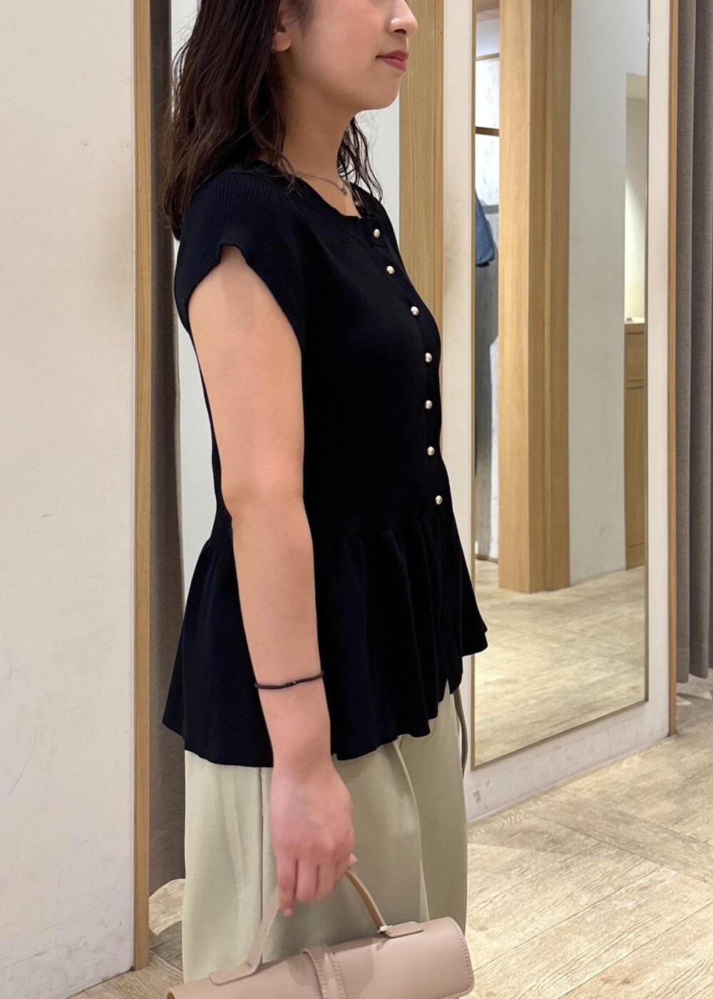 ベージュ系のショルダーバッグ、ブラック系のパンプス、グリーン系のスラックスを着用したレディースの夏コーディネートの8枚目の写真