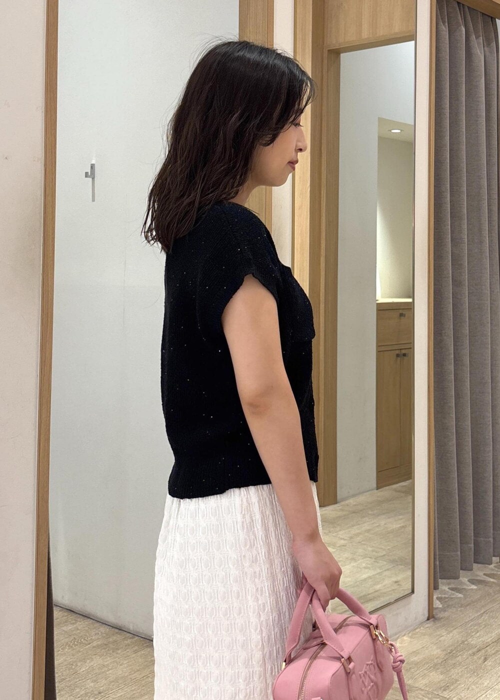 ホワイト系のスカート、ブラック系のカーディガン/ボレロ、ブラック系のパンプスを着用したレディースの夏コーディネートの6枚目の写真