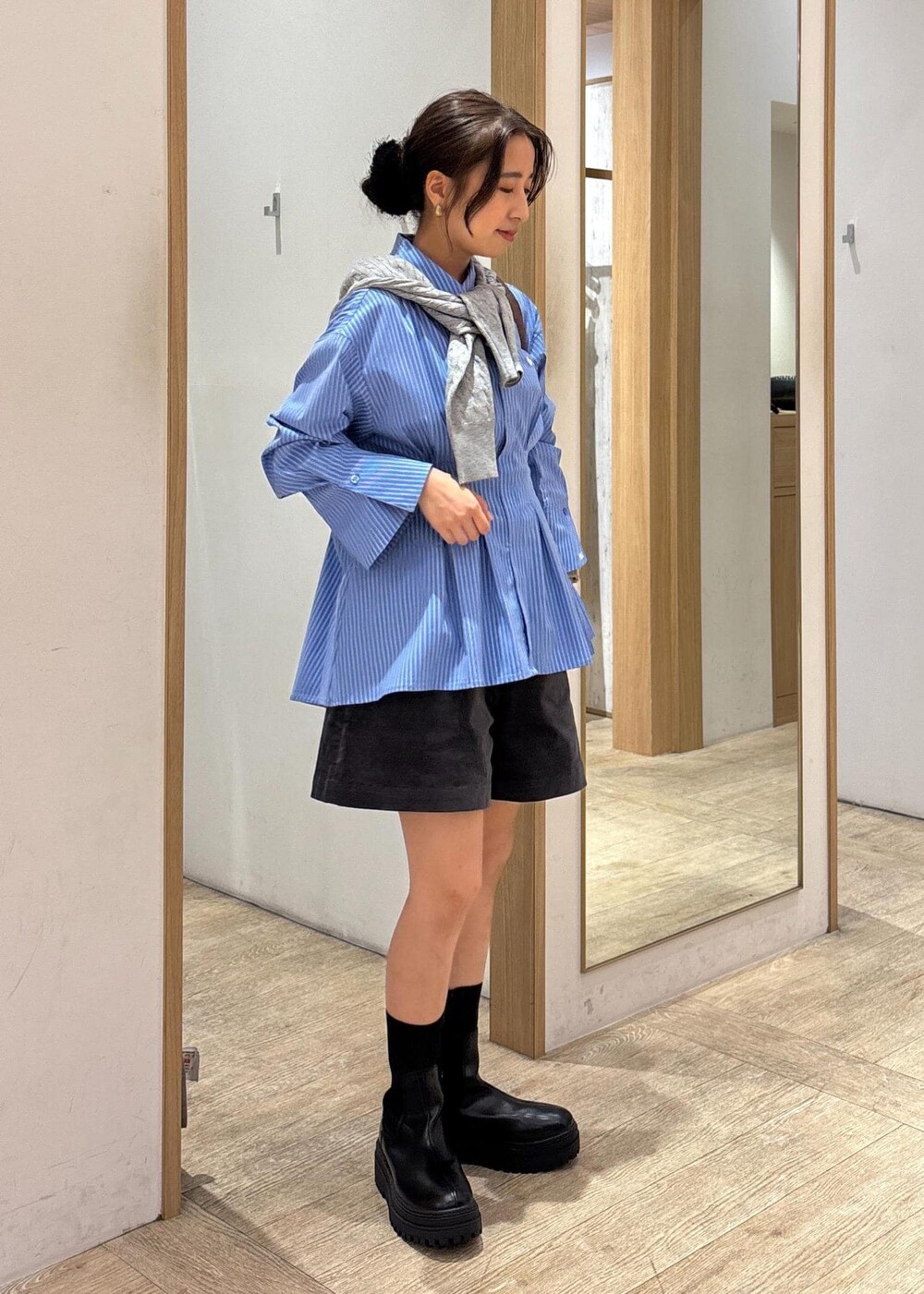 ブラック系のブーツ、ブルー系のシャツ/ブラウス、グレー系のカーディガン/ボレロを着用したレディースの秋コーディネートの2枚目の写真