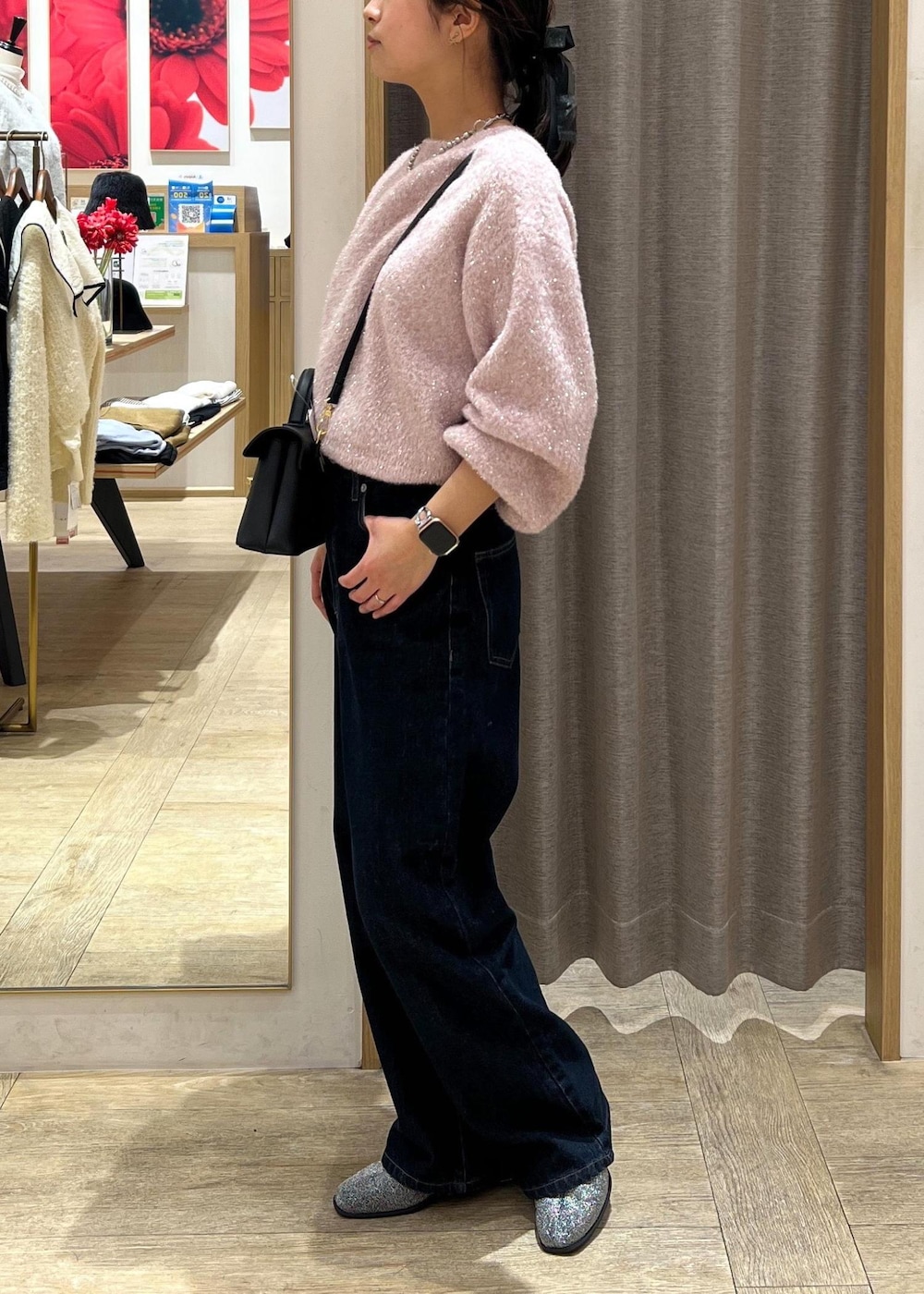ブラック系のショルダーバッグ、シルバー系のブーツ、ブルー系のデニムパンツを着用したレディースの冬コーディネートの3枚目の写真