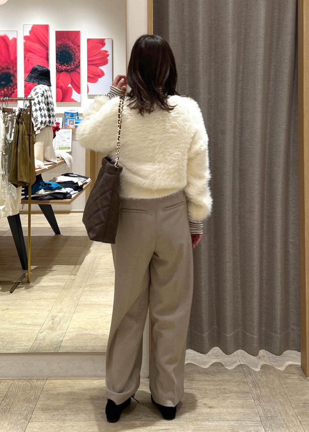 ベージュ系のスラックス、ホワイト系のカーディガン/ボレロ、ブラウン系のショルダーバッグを着用したレディースの冬コーディネートの4枚目の写真