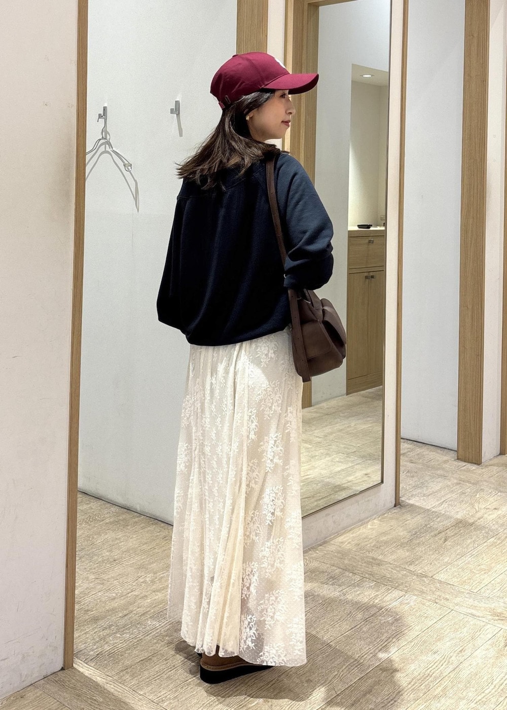 ブラウン系のショルダーバッグ、ベージュ系のローファー、ホワイト系のスカートを着用したレディースの秋コーディネートの4枚目の写真