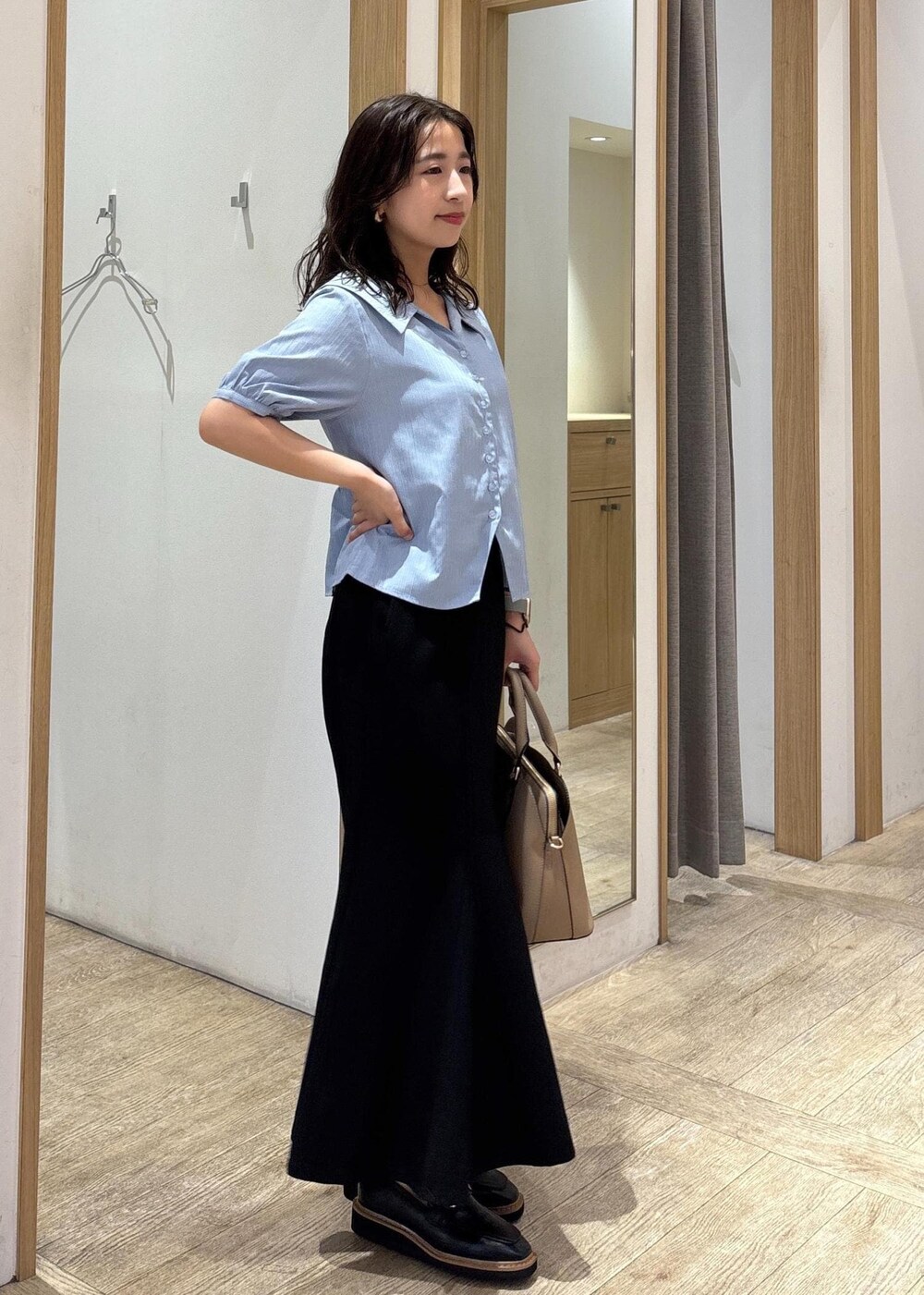 ベージュ系のボストンバッグ、ブラック系のスカート、ブラック系のローファーを着用したレディースの秋コーディネートの4枚目の写真