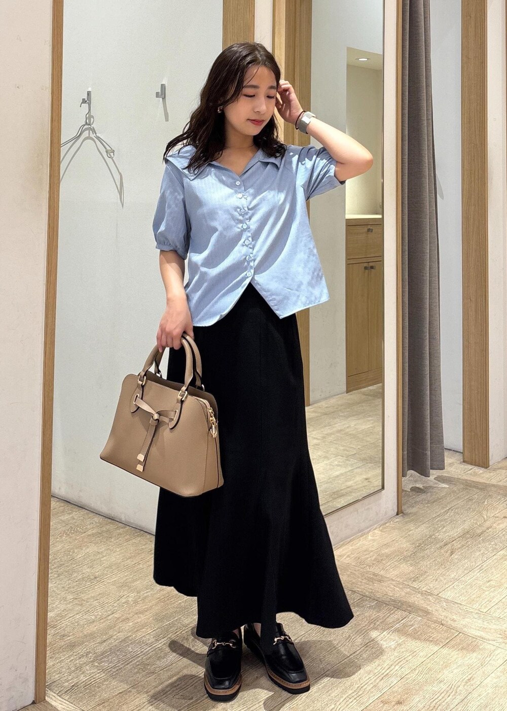 ベージュ系のボストンバッグ、ブラック系のスカート、ブラック系のローファーを着用したレディースの秋コーディネートの9枚目の写真