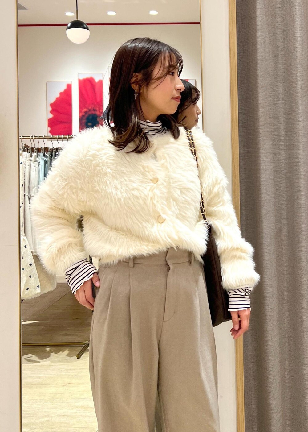 ベージュ系のスラックス、ホワイト系のカーディガン/ボレロ、ブラウン系のショルダーバッグを着用したレディースの冬コーディネートの6枚目の写真