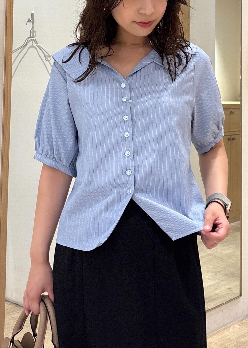 ベージュ系のボストンバッグ、ブラック系のスカート、ブラック系のローファーを着用したレディースの秋コーディネートの5枚目の写真