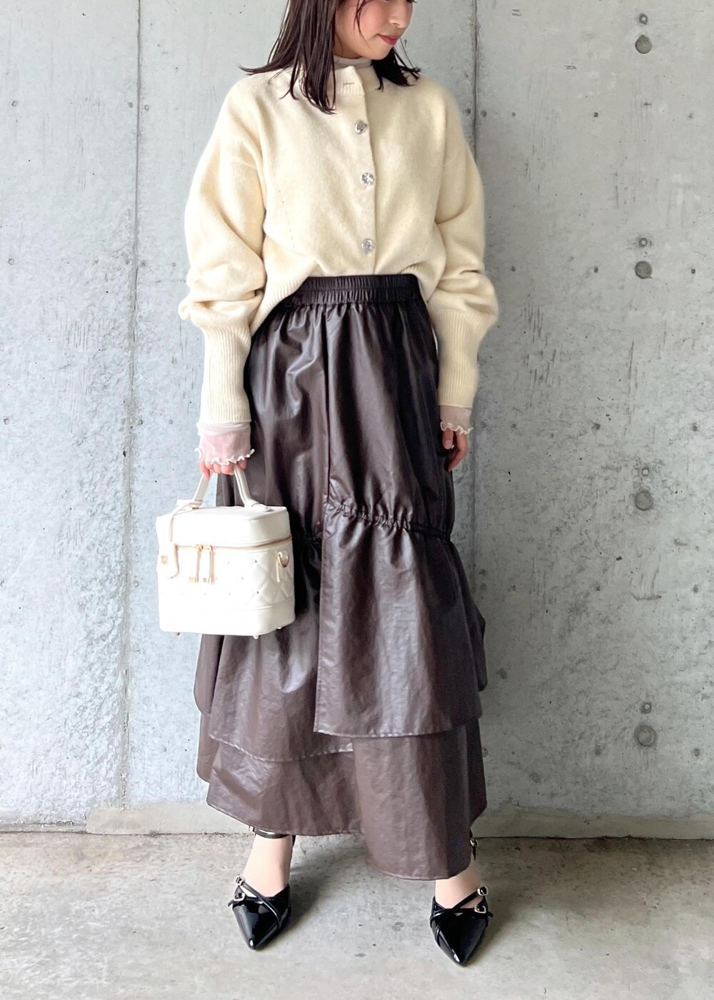 ブラウン系のスカート、ベージュ系のTシャツ/カットソー、ブラック系のパンプスを着用したレディースの冬コーディネートの2枚目の写真