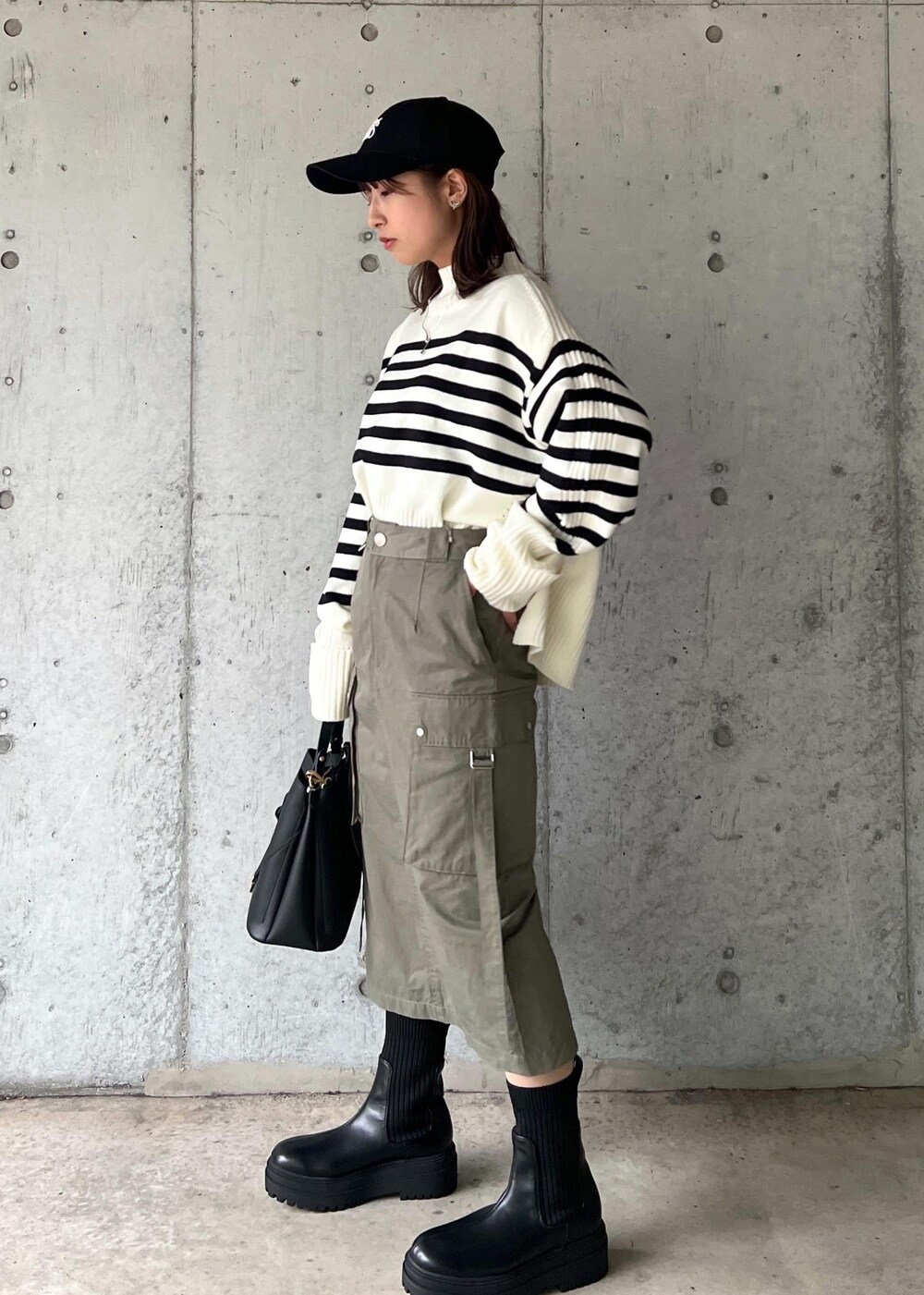 ブラック系のブーツ、グリーン系のスカート、ホワイト系のニット/セーターを着用したレディースの秋コーディネートの3枚目の写真