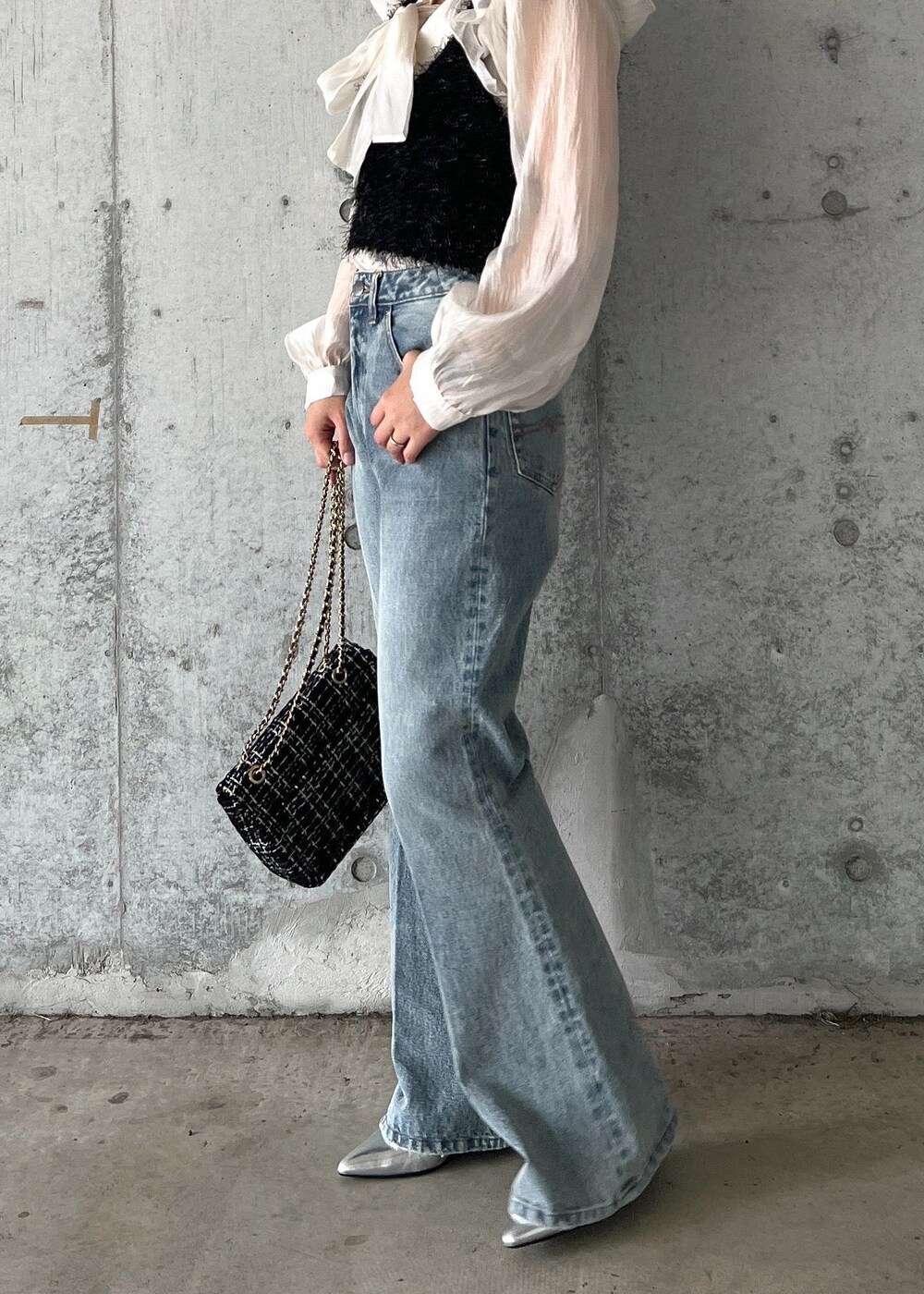 ブルー系のデニムパンツ、ブラック系のキャミソール、シルバー系のブーツを着用したレディースの秋コーディネートの4枚目の写真