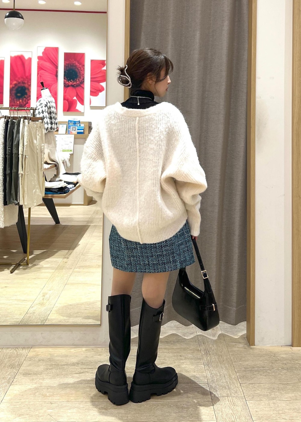 ブラック系のブーツ、ブルー系のスカート、ホワイト系のカーディガン/ボレロを着用したレディースの冬コーディネートの5枚目の写真