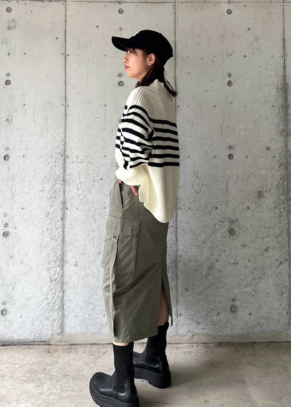 ブラック系のブーツ、グリーン系のスカート、ホワイト系のニット/セーターを着用したレディースの秋コーディネートの4枚目の写真