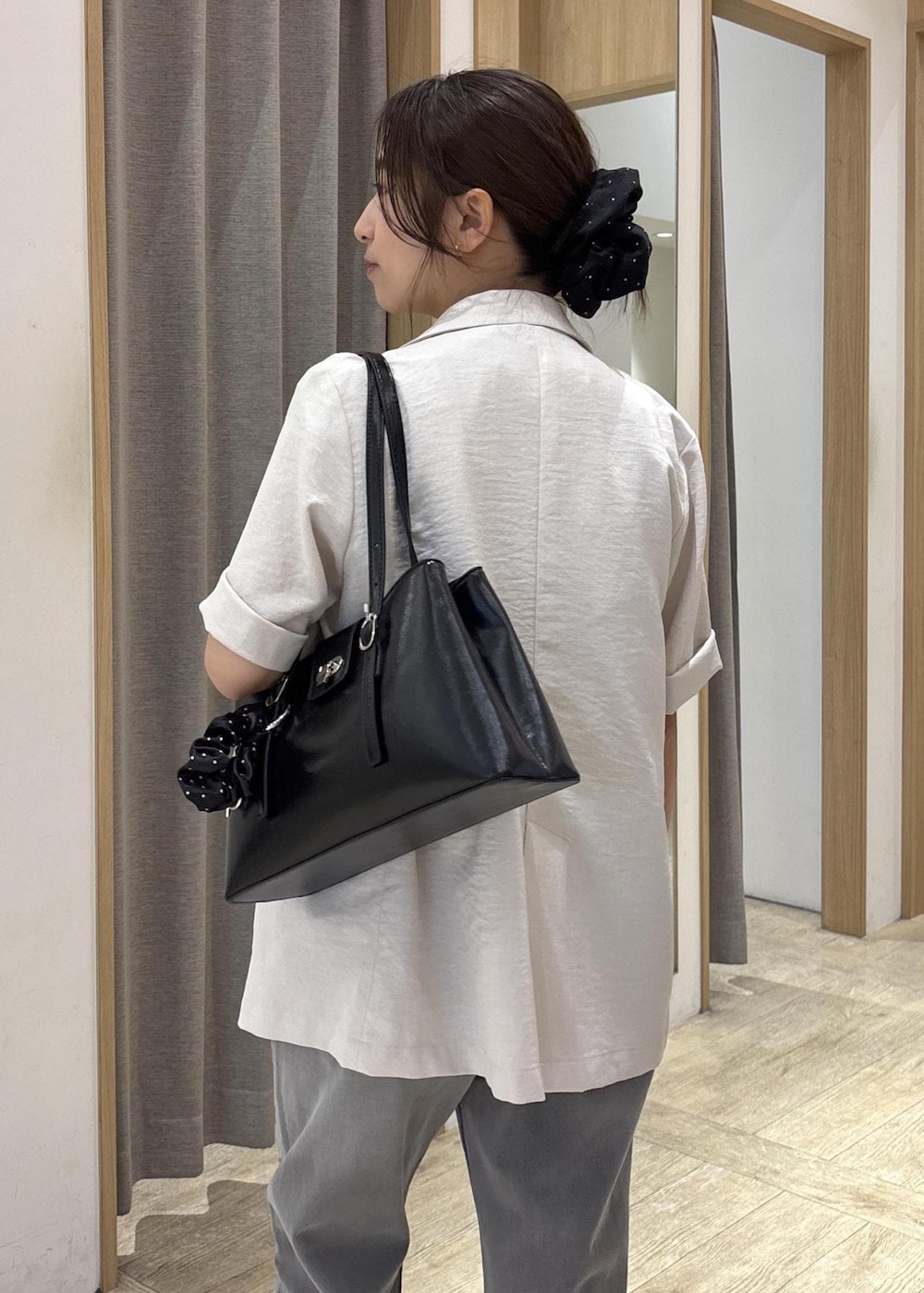 ブラック系のトートバッグ、ホワイト系のテーラードジャケット、グレー系のデニムパンツを着用したレディースの夏コーディネートの8枚目の写真