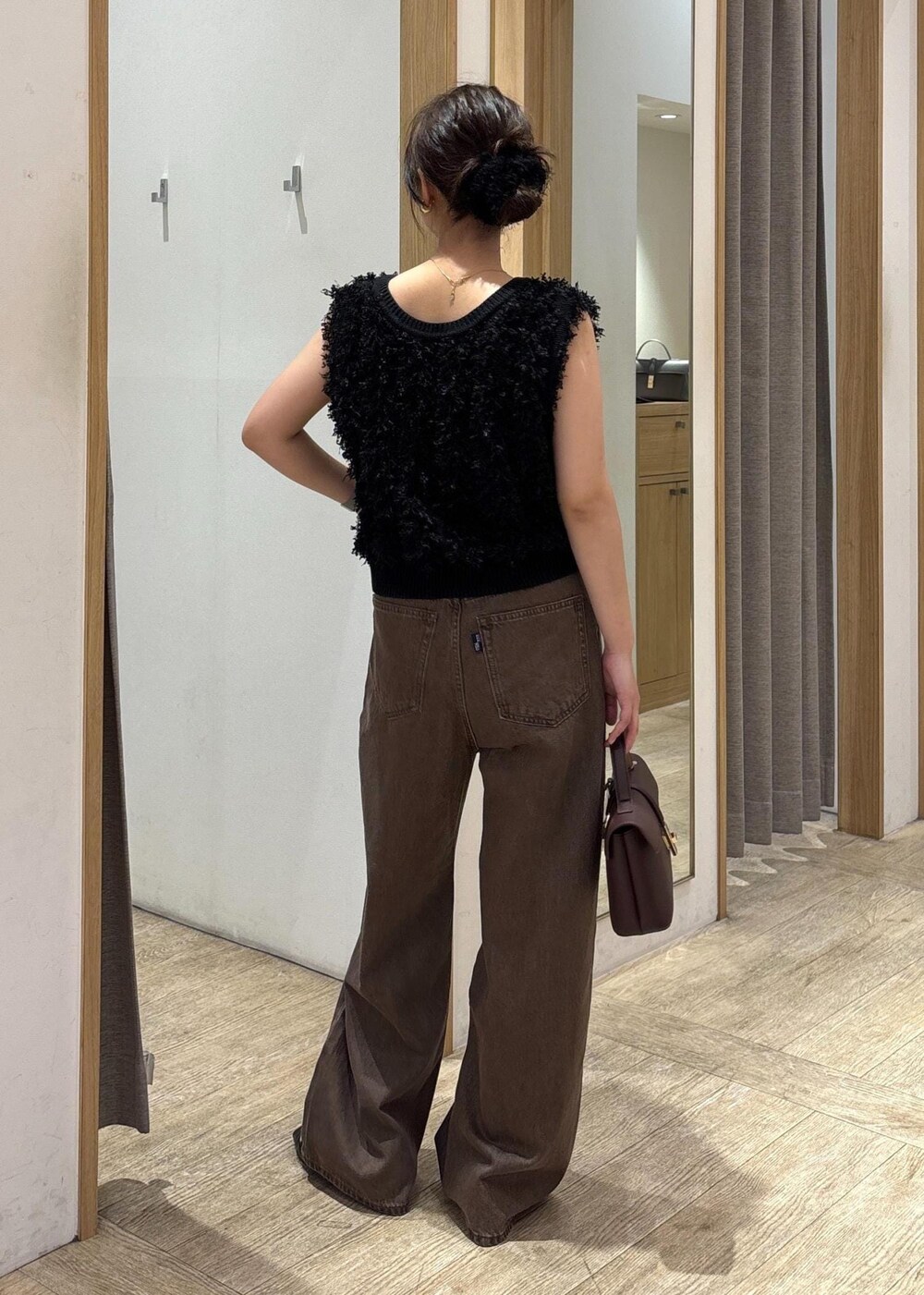 ブラウン系のショルダーバッグ、ブラック系のパンプス、ブラック系のベストを着用したレディースの秋コーディネートの3枚目の写真