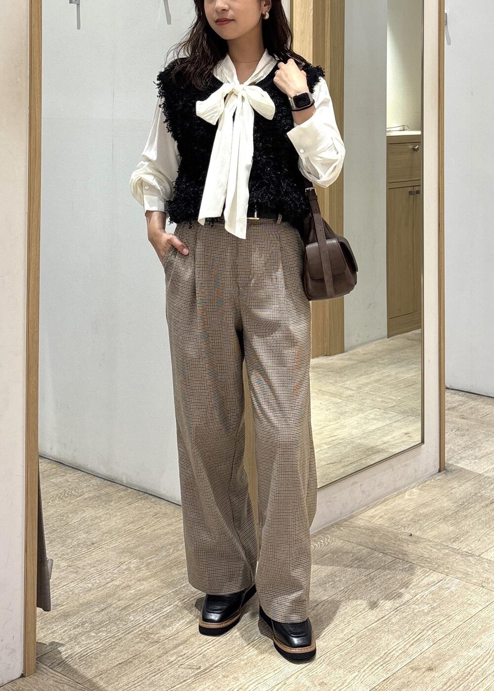 ベージュ系のスラックス、ブラウン系のショルダーバッグ、ブラック系のベストを着用したレディースの秋コーディネートの10枚目の写真