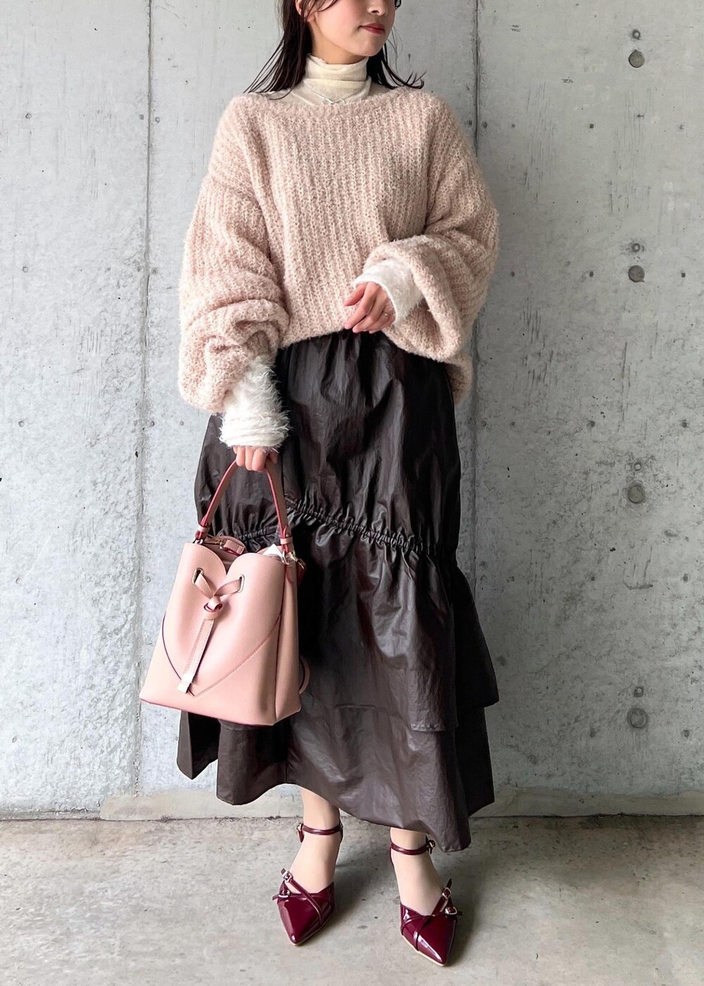 ピンク系のショルダーバッグ、ホワイト系のニット/セーター、ベージュ系のニット/セーターを着用したレディースの冬コーディネートの3枚目の写真