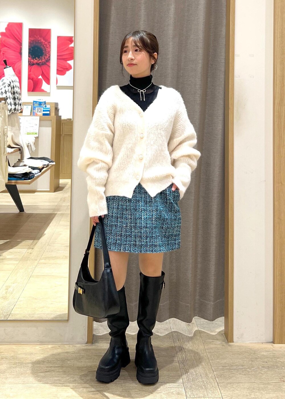 ブラック系のブーツ、ブルー系のスカート、ホワイト系のカーディガン/ボレロを着用したレディースの冬コーディネートの2枚目の写真