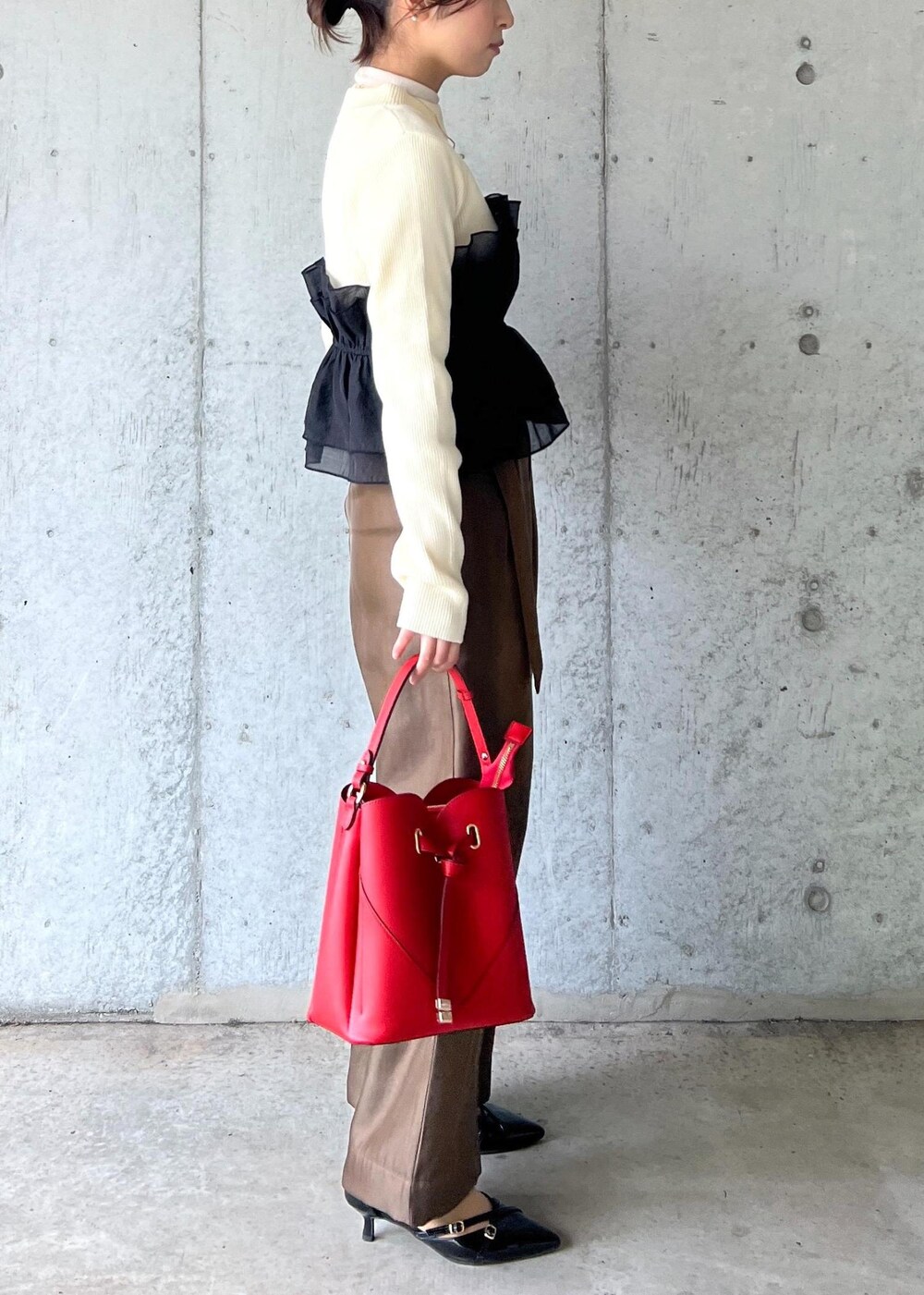 レッド系のショルダーバッグ、ブラック系のパンプス、ホワイト系のニット/セーターを着用したレディースの冬コーディネートの4枚目の写真