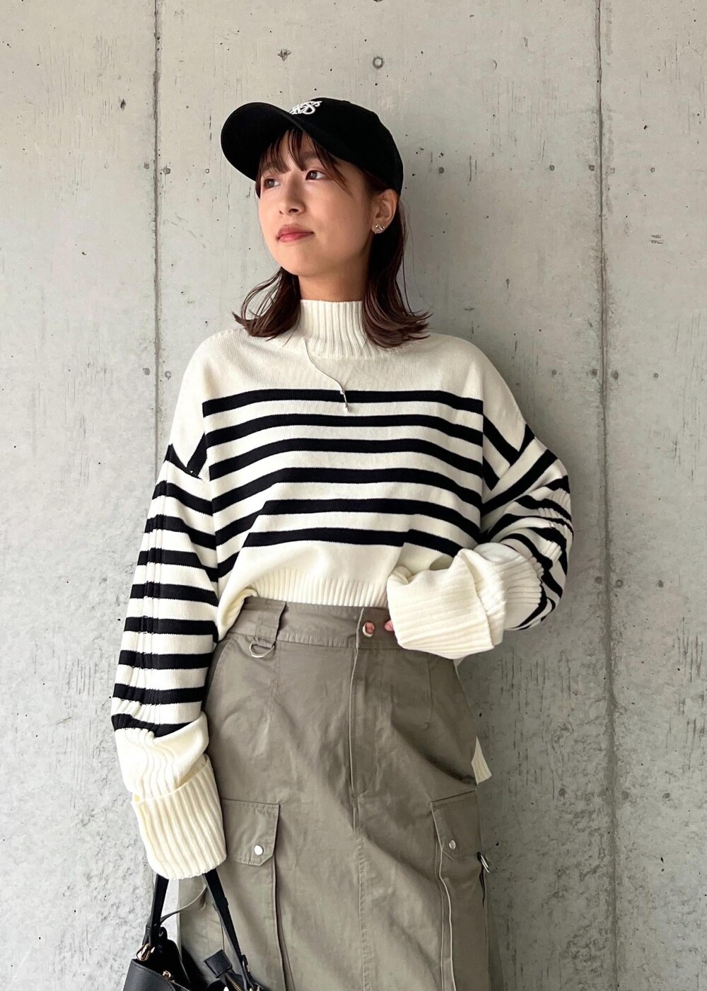 ブラック系のブーツ、グリーン系のスカート、ホワイト系のニット/セーターを着用したレディースの秋コーディネートの6枚目の写真