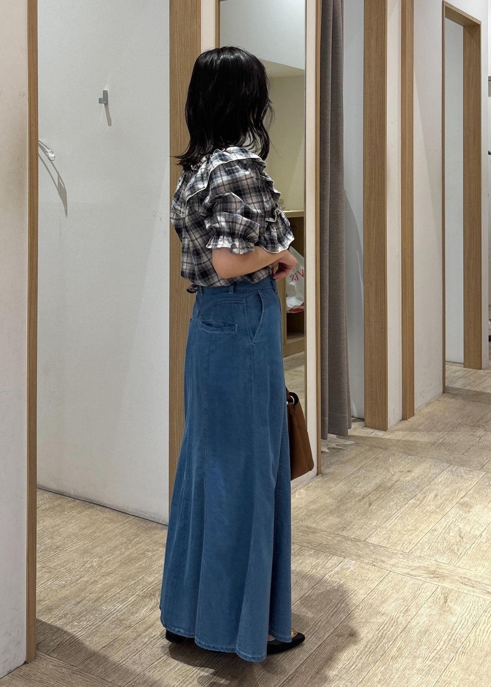 ブラック系のバレエシューズ、ブルー系のデニムスカート、ブラウン系のショルダーバッグを着用したレディースの夏コーディネートの4枚目の写真