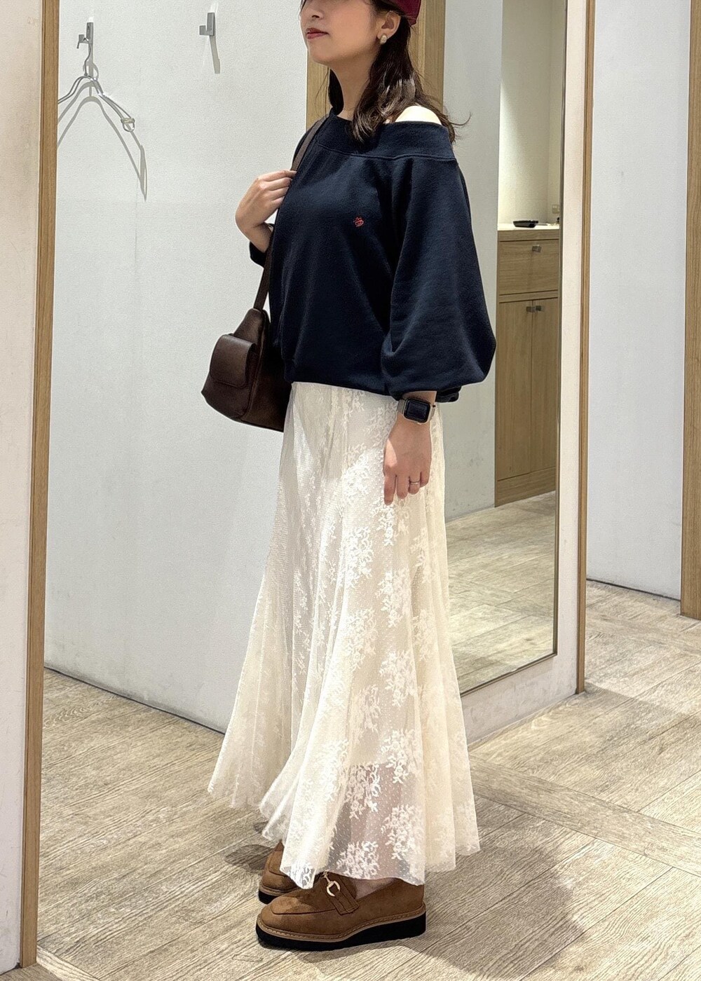 ブラウン系のショルダーバッグ、ベージュ系のローファー、ホワイト系のスカートを着用したレディースの秋コーディネートの2枚目の写真