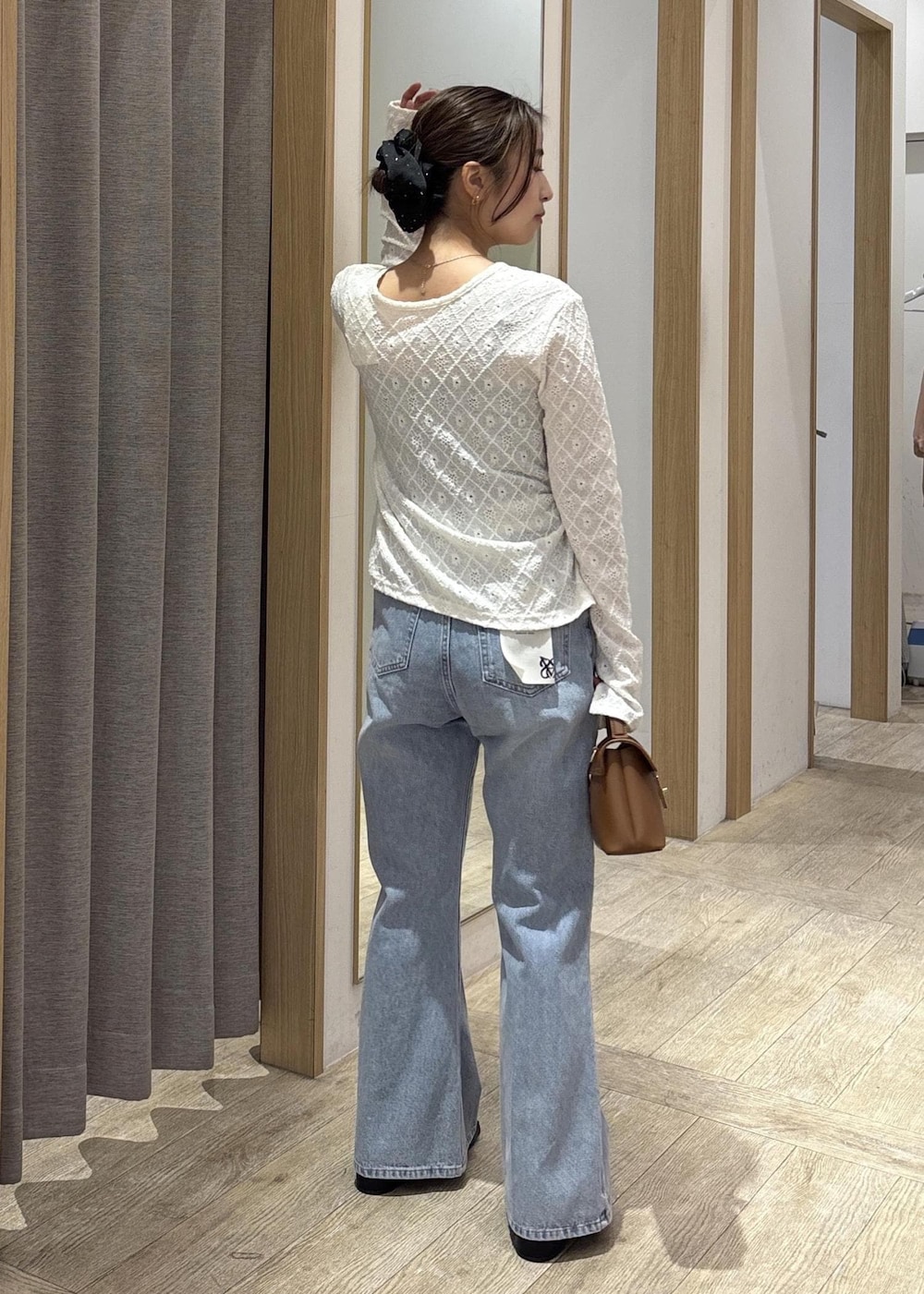 イエロー系のショルダーバッグ、ホワイト系のカーディガン/ボレロ、ブルー系のデニムパンツを着用したレディースの春コーディネートの4枚目の写真