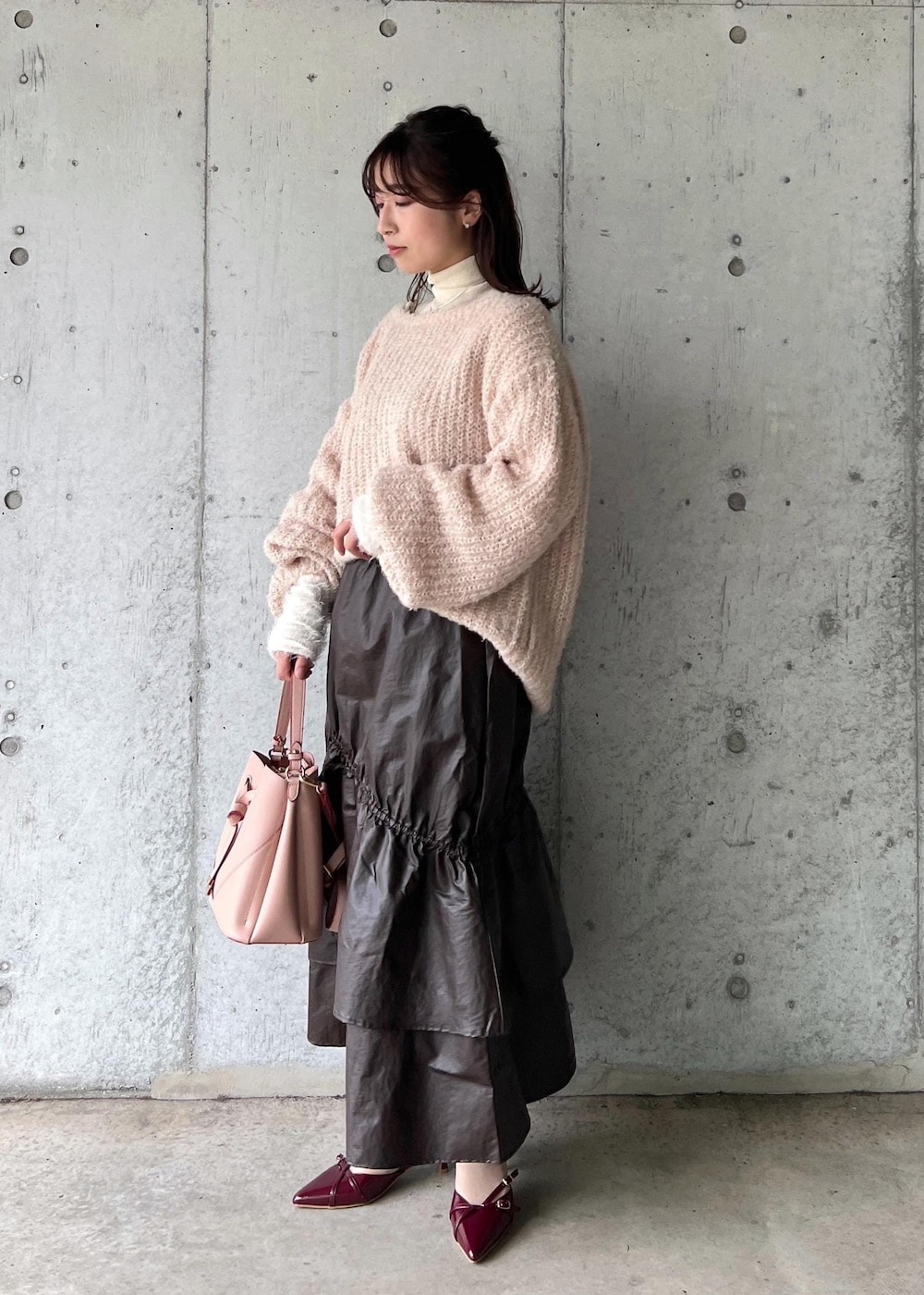 ピンク系のショルダーバッグ、ホワイト系のニット/セーター、ベージュ系のニット/セーターを着用したレディースの冬コーディネートの2枚目の写真