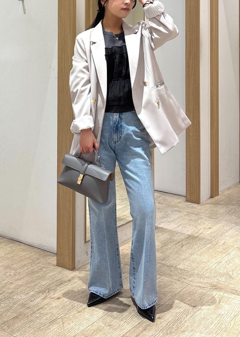 グレー系のショルダーバッグ、ベージュ系のテーラードジャケット、ブルー系のデニムパンツを着用したレディースの春コーディネートの2枚目の写真