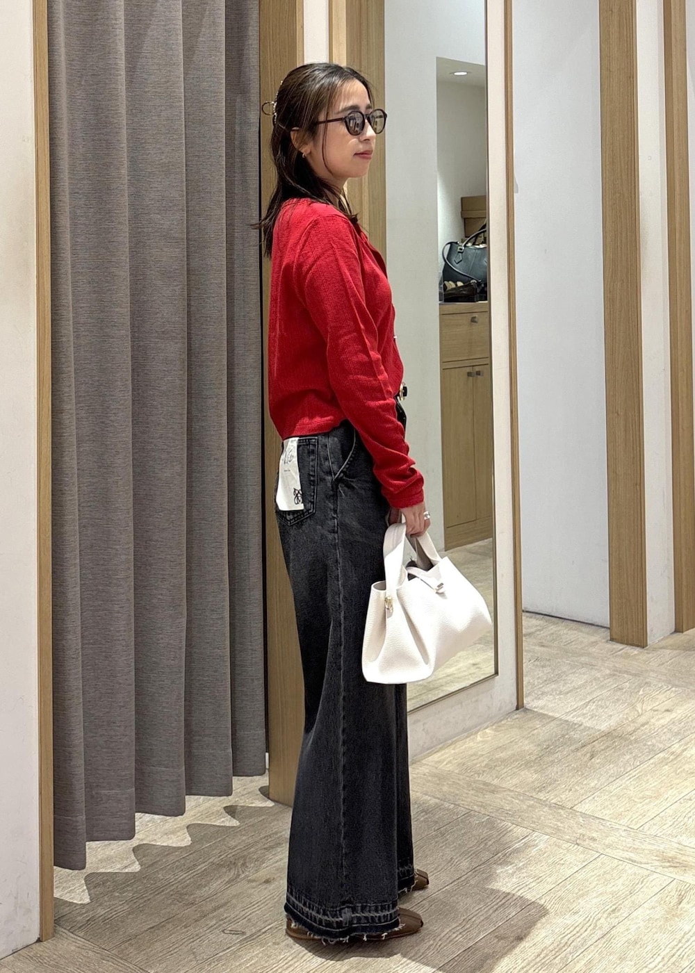 ブラウン系のパンプス、レッド系のカーディガン/ボレロ、ブラック系のデニムパンツを着用したレディースの春コーディネートの3枚目の写真