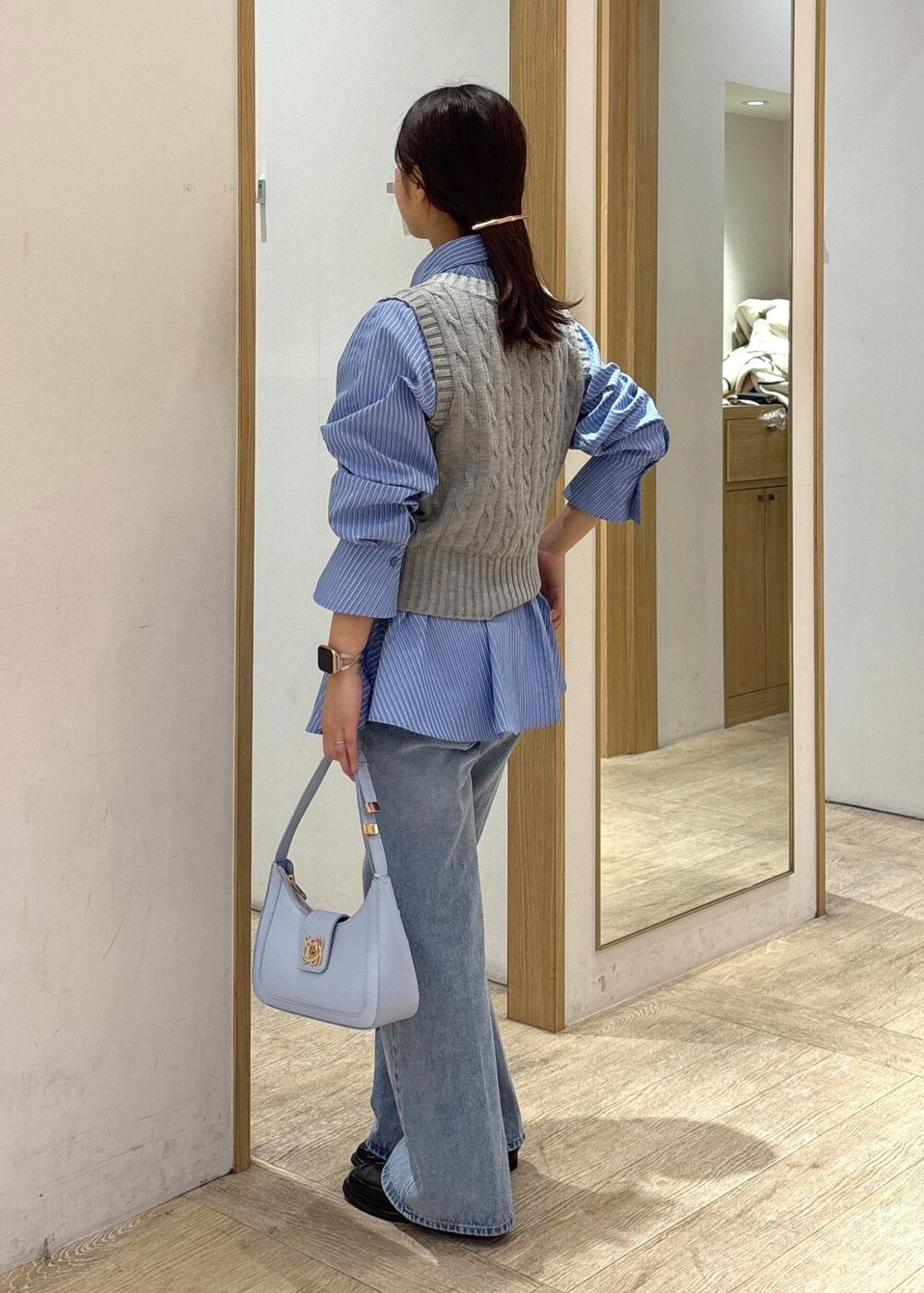 ブルー系のシャツ/ブラウス、グレー系のベスト、ブルー系のデニムパンツを着用したレディースの冬コーディネートの4枚目の写真