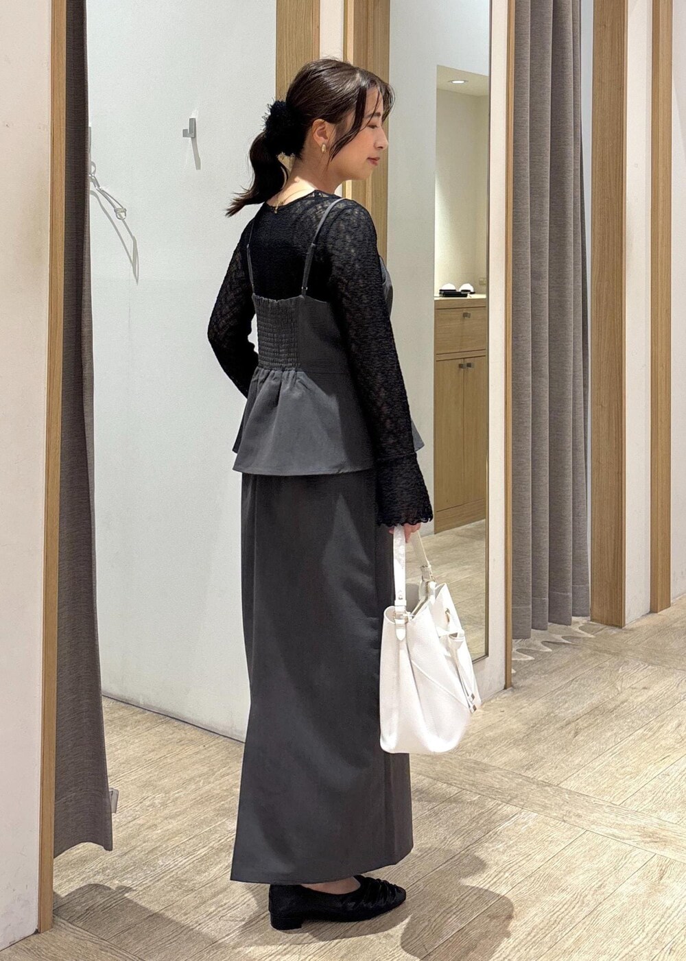 ホワイト系のショルダーバッグ、ブラック系のパンプス、グレー系のワンピースを着用したレディースの秋コーディネートの2枚目の写真