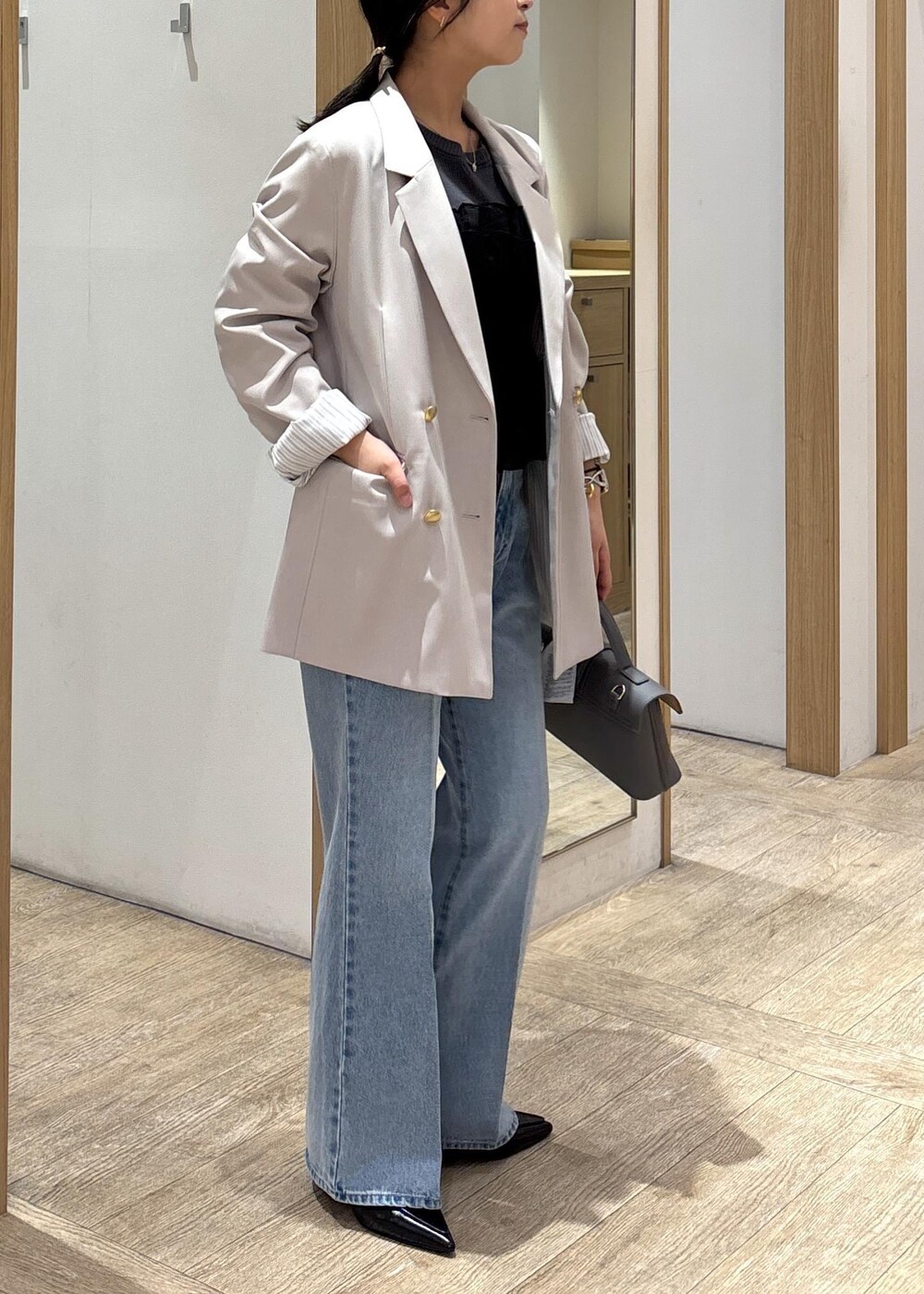 グレー系のショルダーバッグ、ベージュ系のテーラードジャケット、ブルー系のデニムパンツを着用したレディースの春コーディネートの3枚目の写真