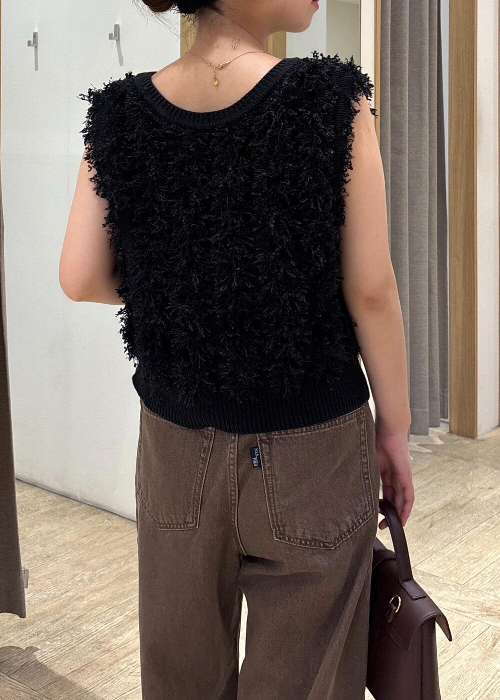 ブラウン系のショルダーバッグ、ブラック系のパンプス、ブラック系のベストを着用したレディースの秋コーディネートの6枚目の写真