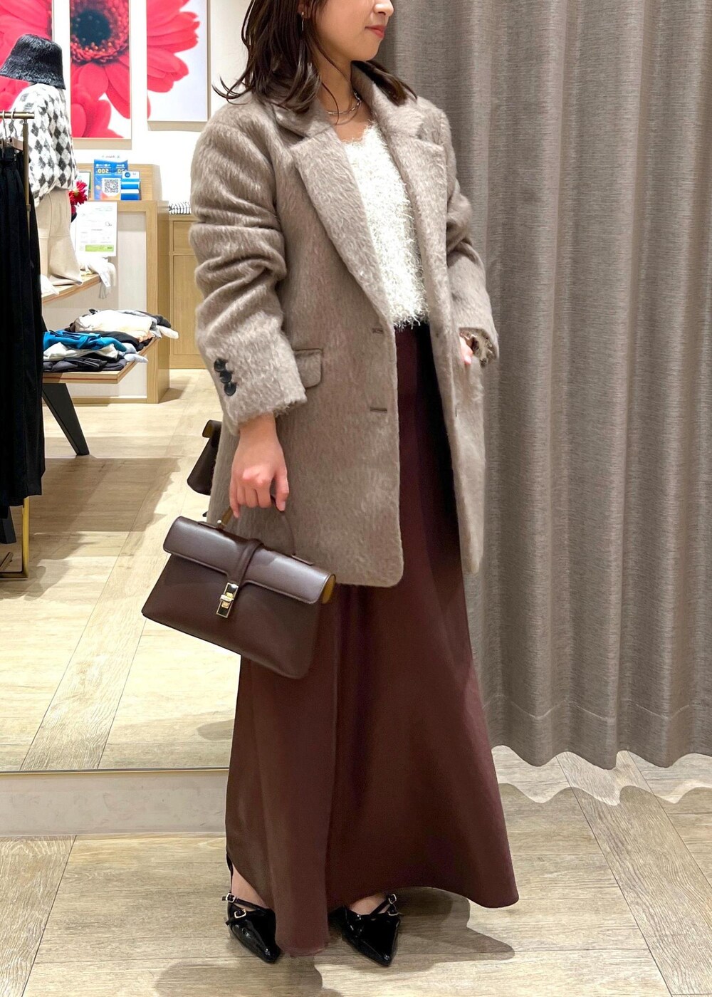 ブラック系のパンプス、ブラウン系のスカート、ホワイト系のニット/セーターを着用したレディースの冬コーディネートの5枚目の写真