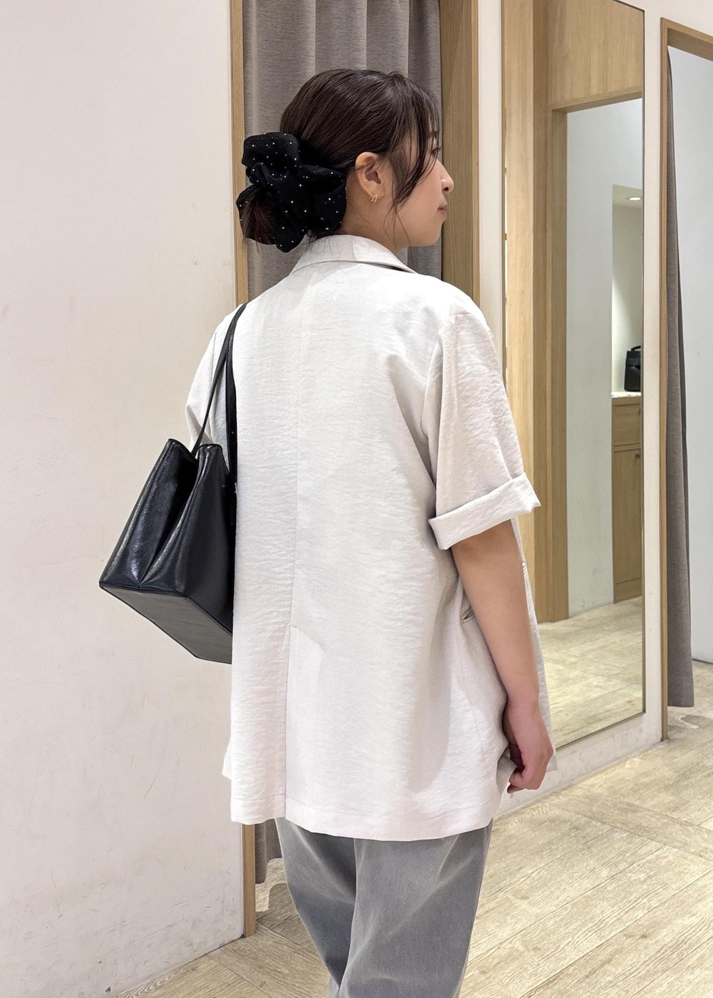 ブラック系のトートバッグ、ホワイト系のテーラードジャケット、グレー系のデニムパンツを着用したレディースの夏コーディネートの7枚目の写真
