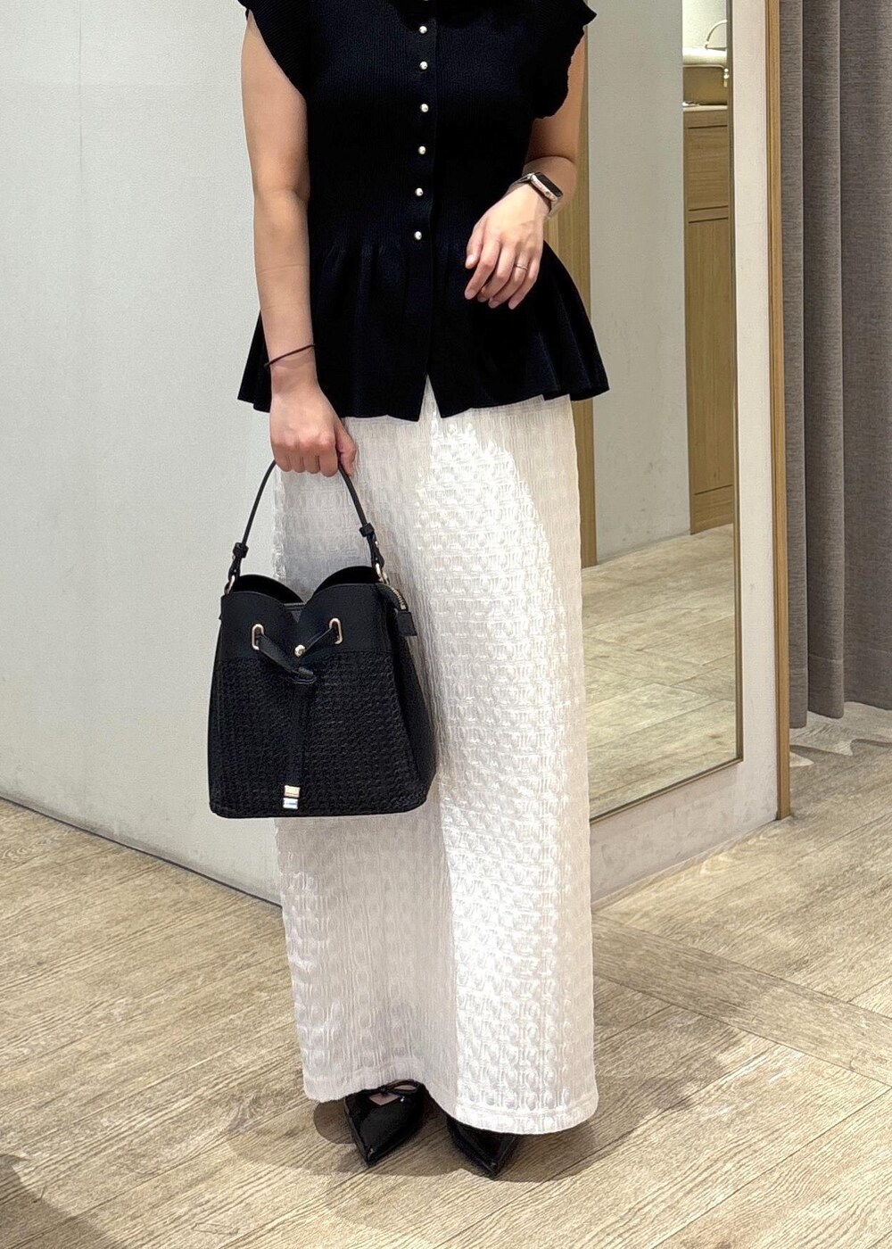 ブラック系のパンプス、ホワイト系のスカート、ブラック系のショルダーバッグを着用したレディースの夏コーディネートの9枚目の写真