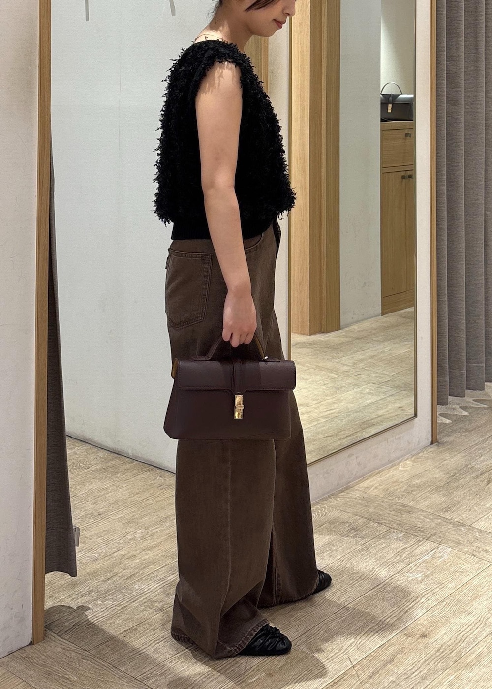 ブラウン系のショルダーバッグ、ブラック系のパンプス、ブラック系のベストを着用したレディースの秋コーディネートの2枚目の写真